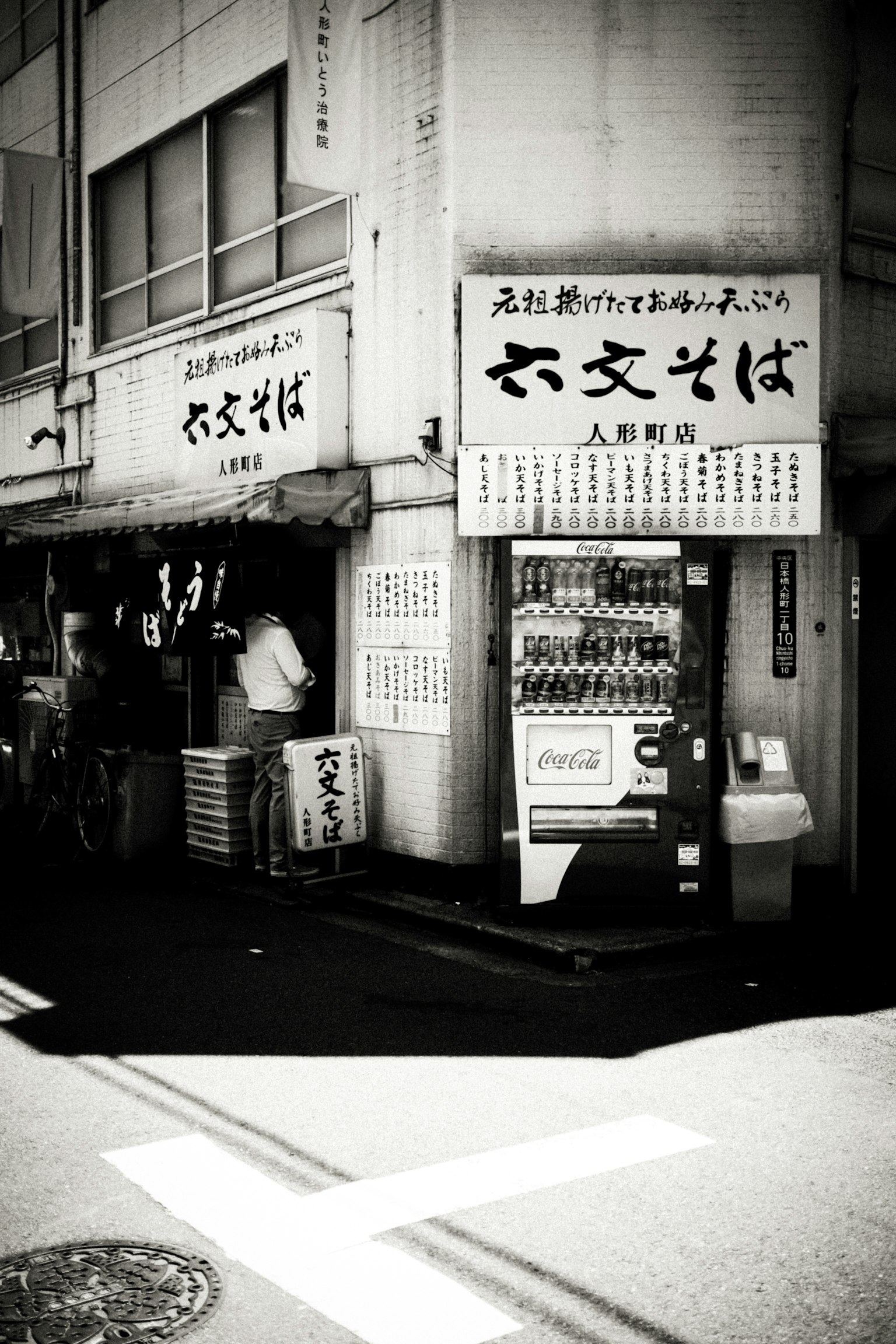 Exterior of a soba restaurant in black and white with a vending machine