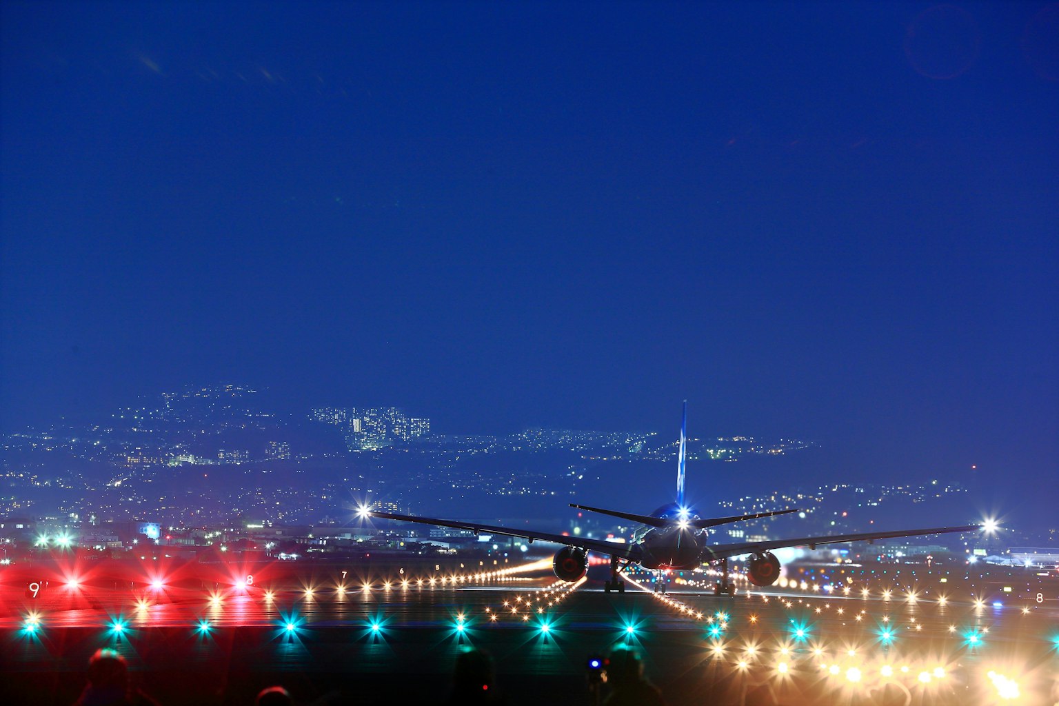 Avion atterrissant sur une piste la nuit avec des lumières de la ville en arrière-plan