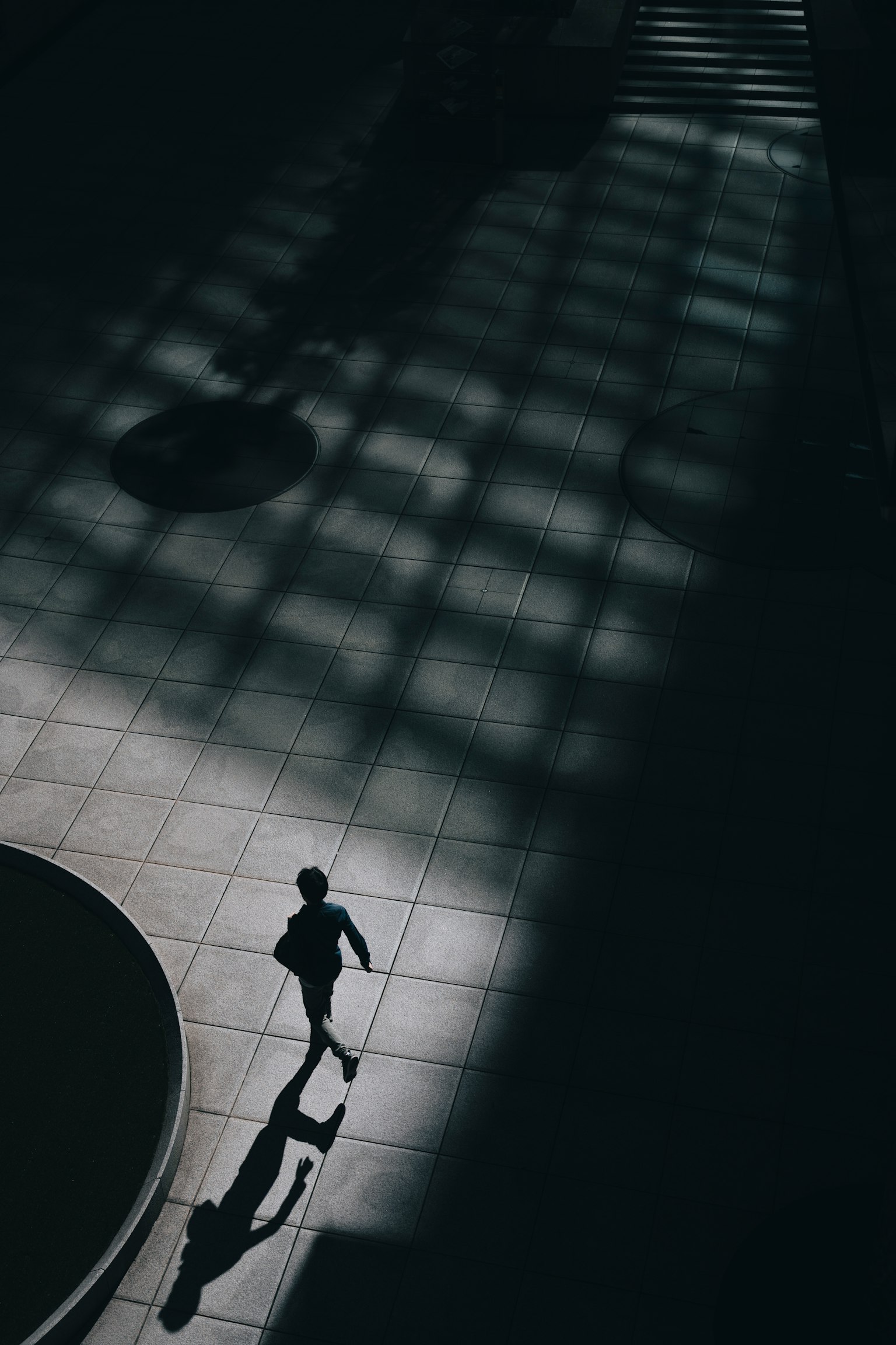Silhouette seseorang yang berjalan dalam bayangan dengan pola cahaya geometris