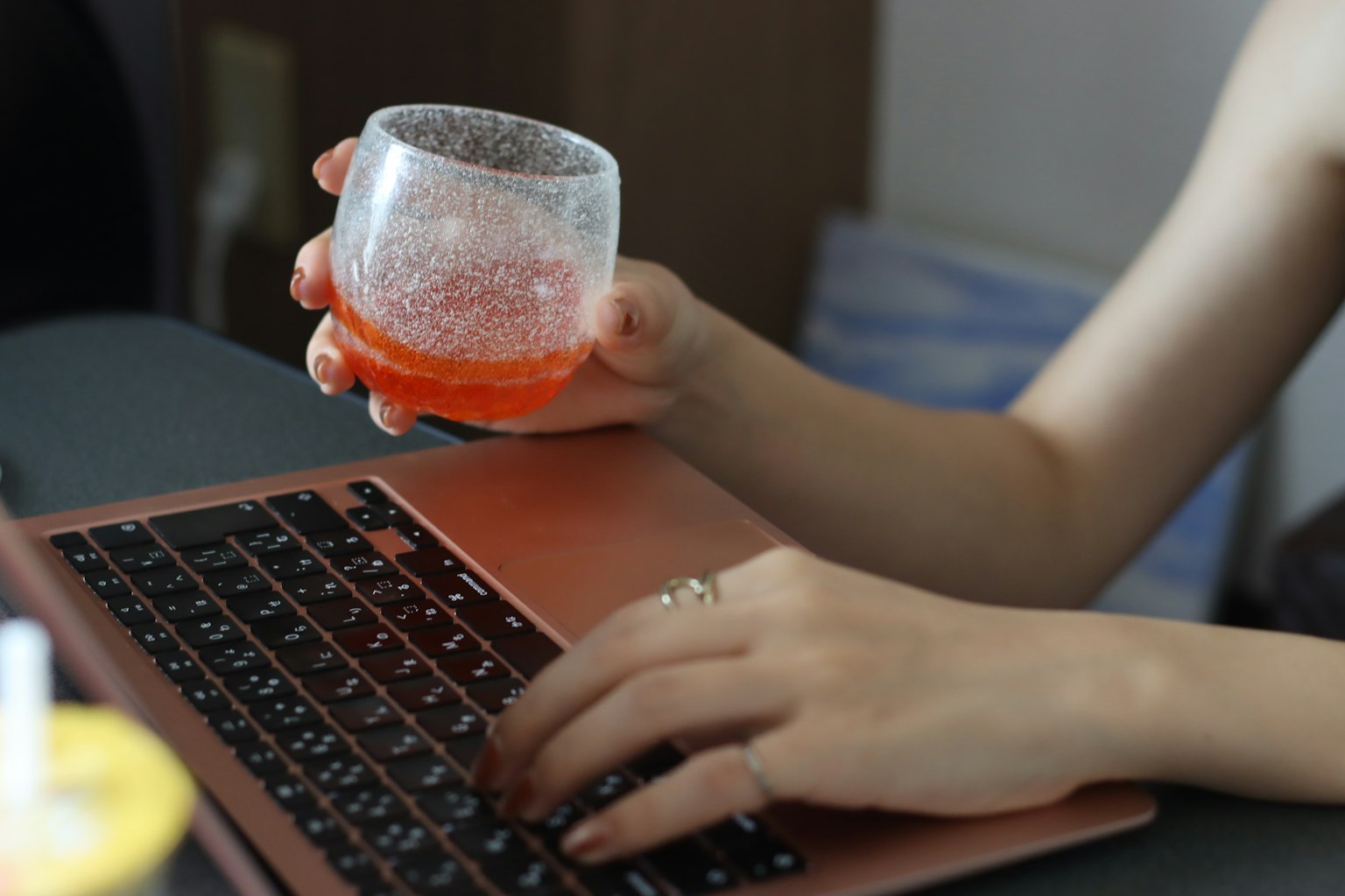 Main tenant un verre avec un clavier d'ordinateur portable en arrière-plan