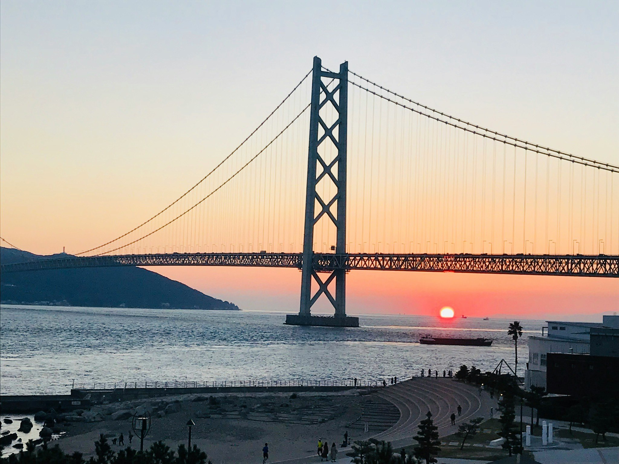 夕日と明石海峡大橋を望む海辺の景色