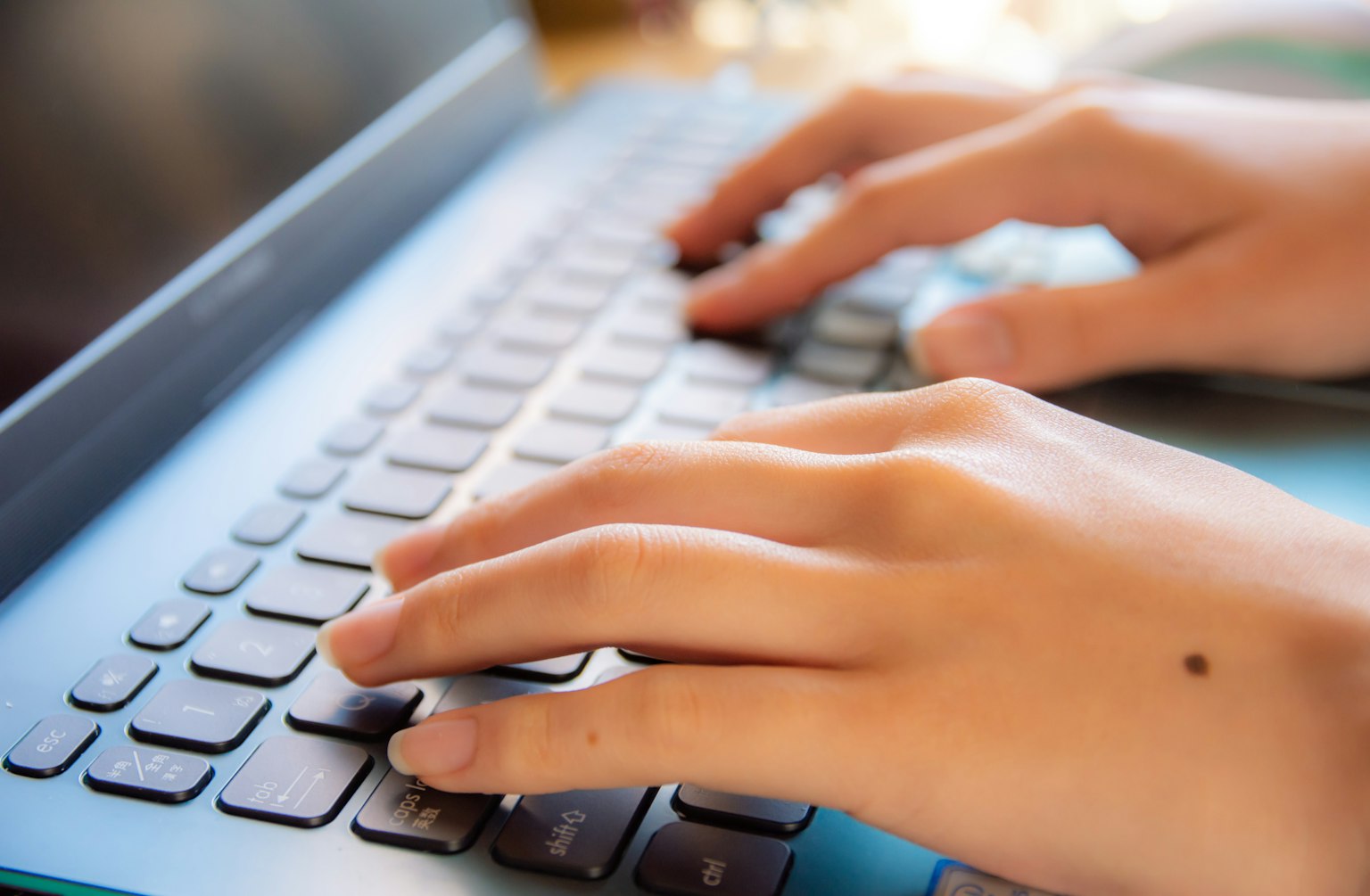 Primo piano di mani che digitano su una tastiera di laptop