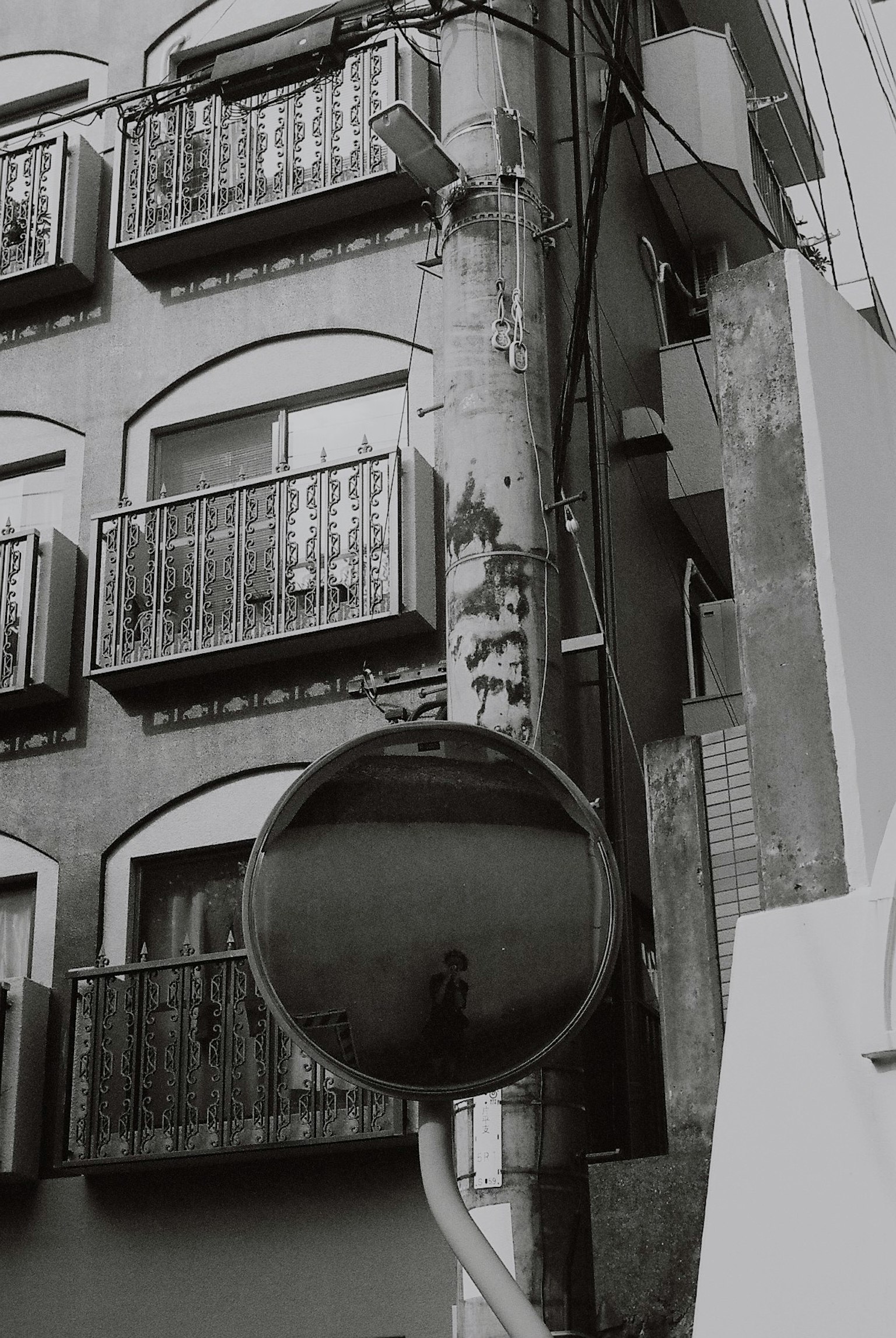 Black and white photo of an old building showing balconies and a mirror reflection