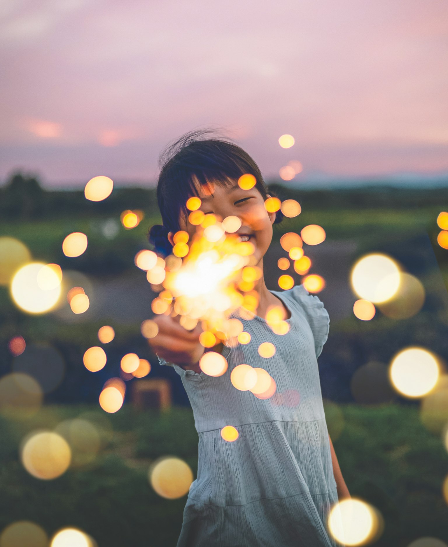 Una ragazza che tiene felicemente un fuoco d'artificio con uno sfondo di tramonto