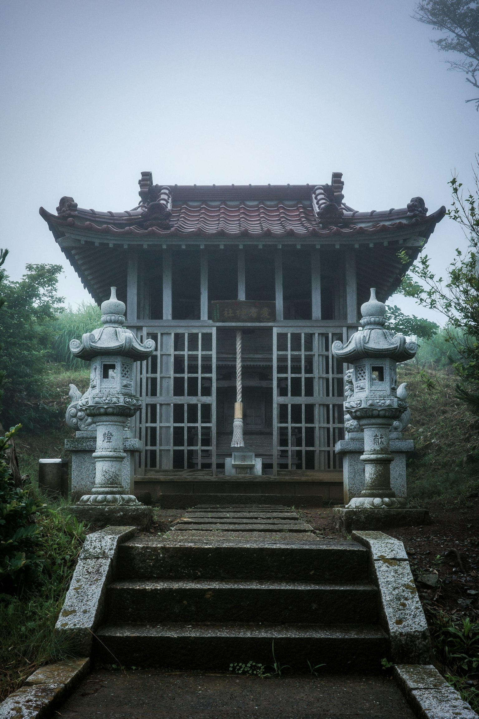 古老的神社建築與石燈籠籠罩在霧中