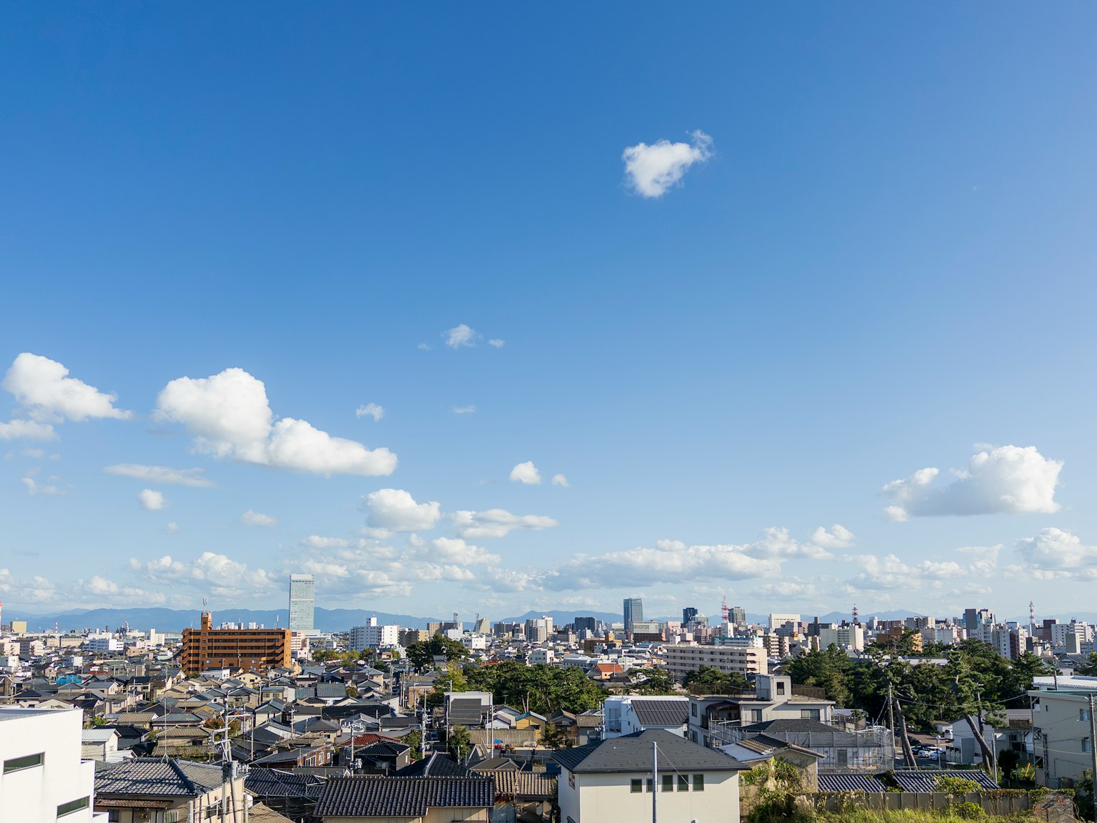 ทิวทัศน์เมืองใต้ท้องฟ้าสีฟ้าพร้อมการผสมผสานของอาคารแบบดั้งเดิมและสมัยใหม่