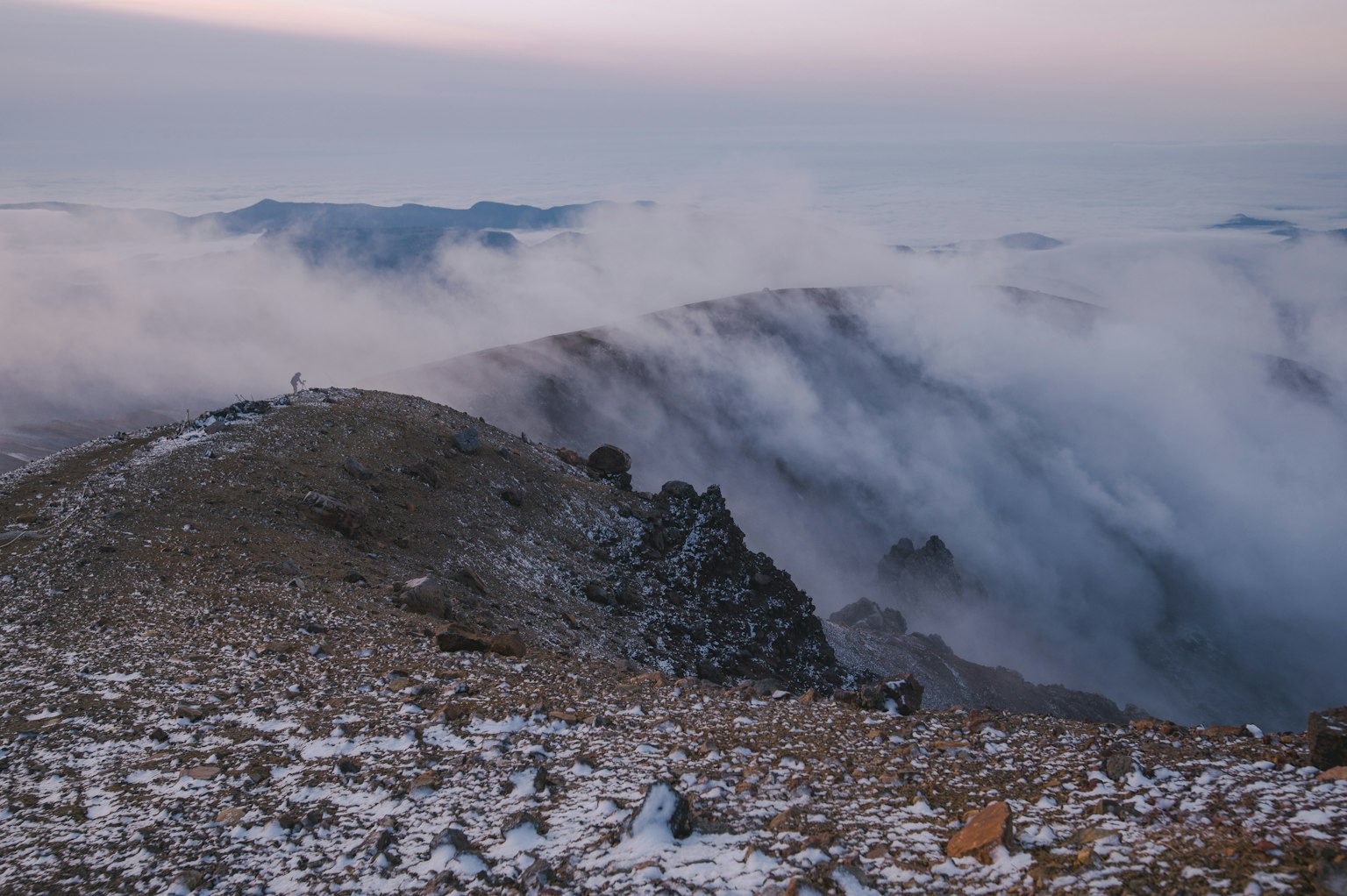 Paisaje montañoso cubierto de nieve con colinas envueltas en niebla