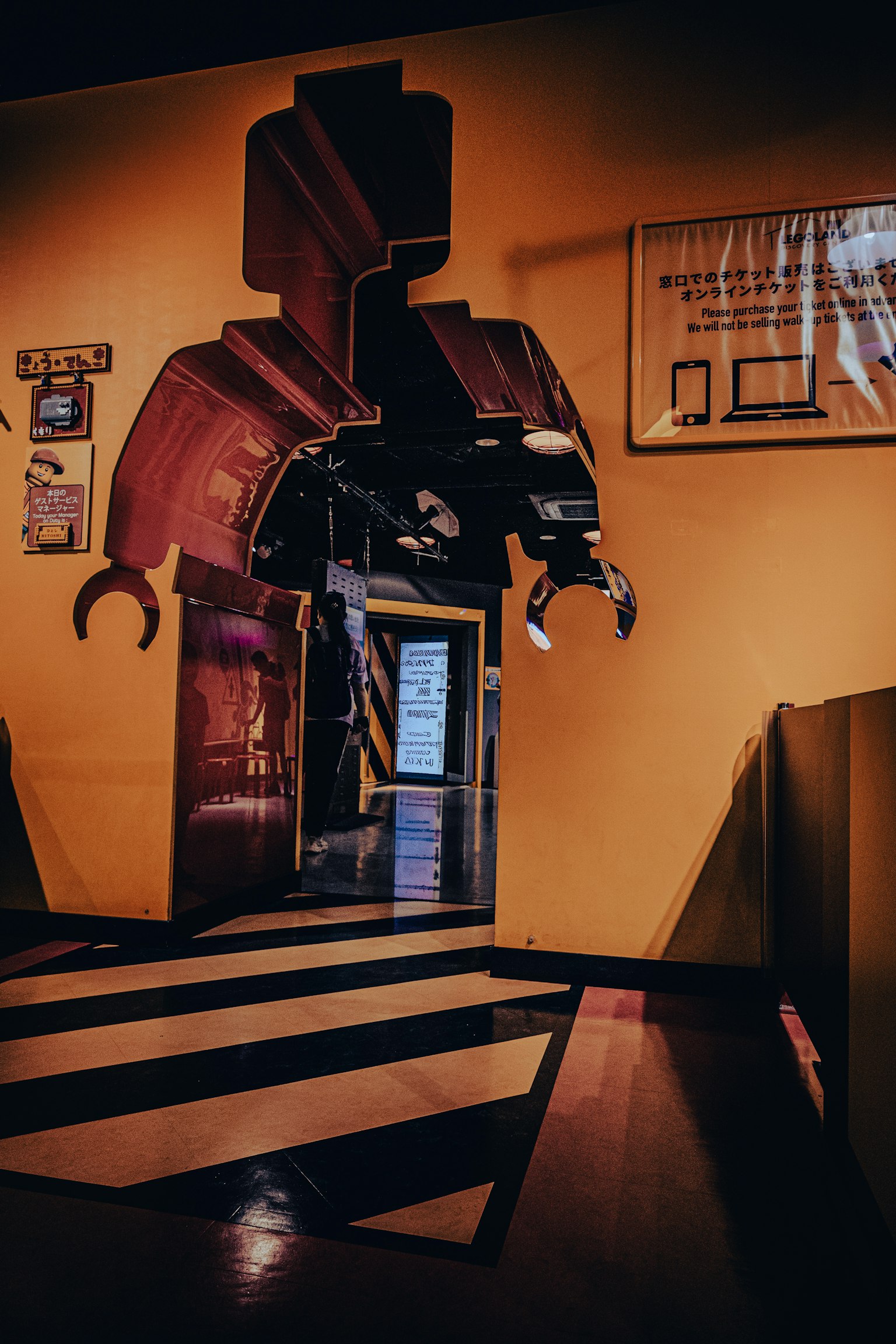 Representación artística de una figura similar a un robot en una pared amarilla con una puerta debajo
