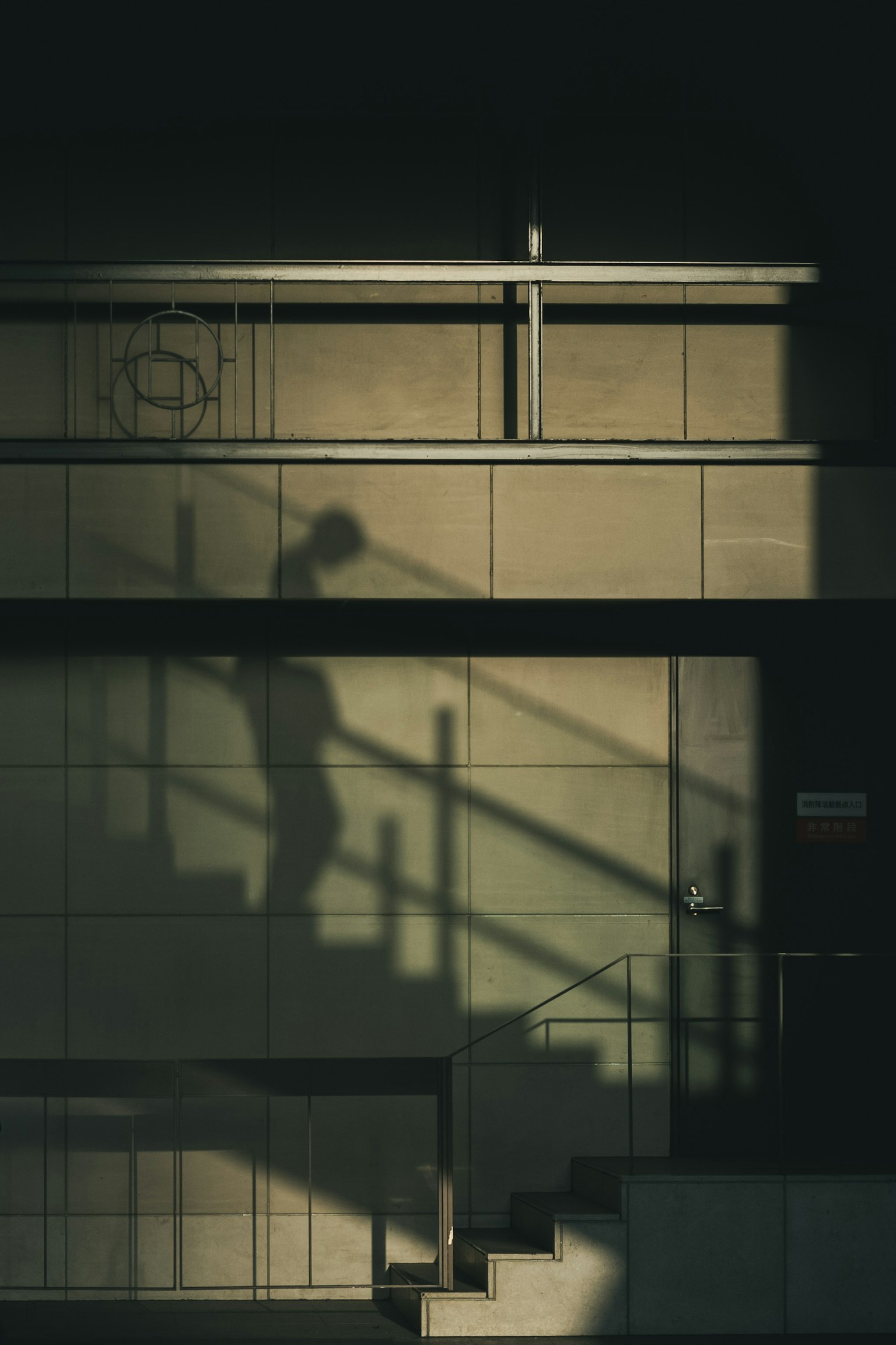 Sombra de una persona bajando escaleras en una pared de edificio