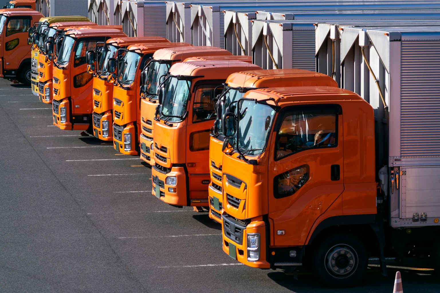 Mehrere orangefarbene Lkw sauber auf einem Parkplatz geparkt