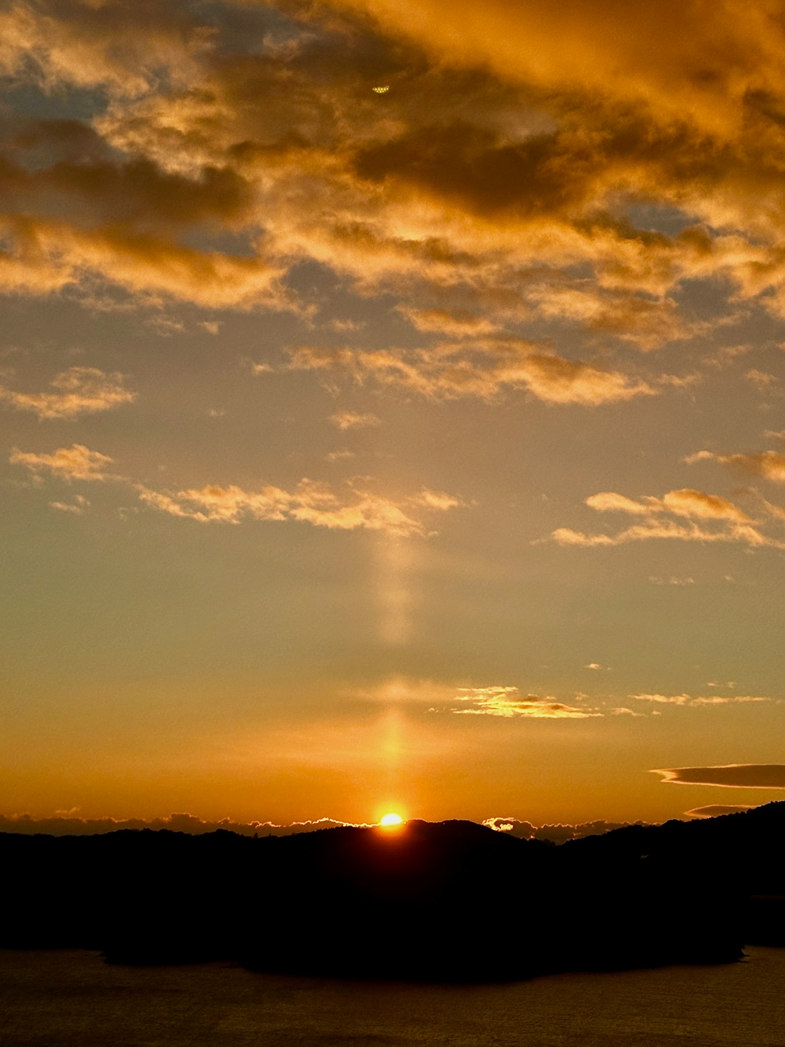 Beautiful sunset landscape with sun rising between mountains and orange clouds