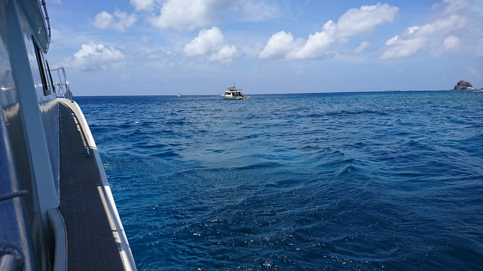 Sebuah perahu mengapung di laut biru di bawah langit dengan awan putih