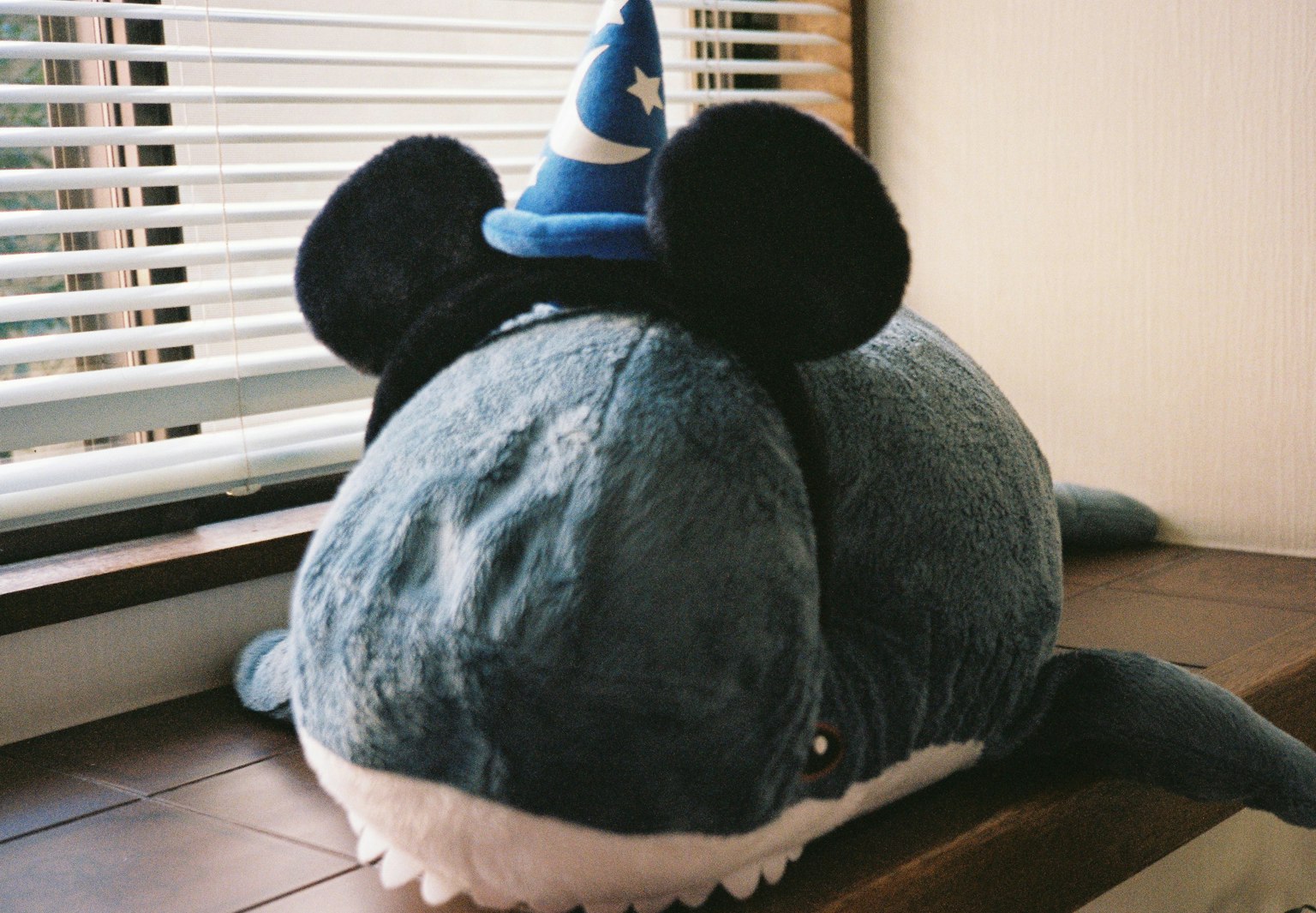 Une baleine en peluche bleue portant des oreilles de Mickey et un chapeau de sorcier