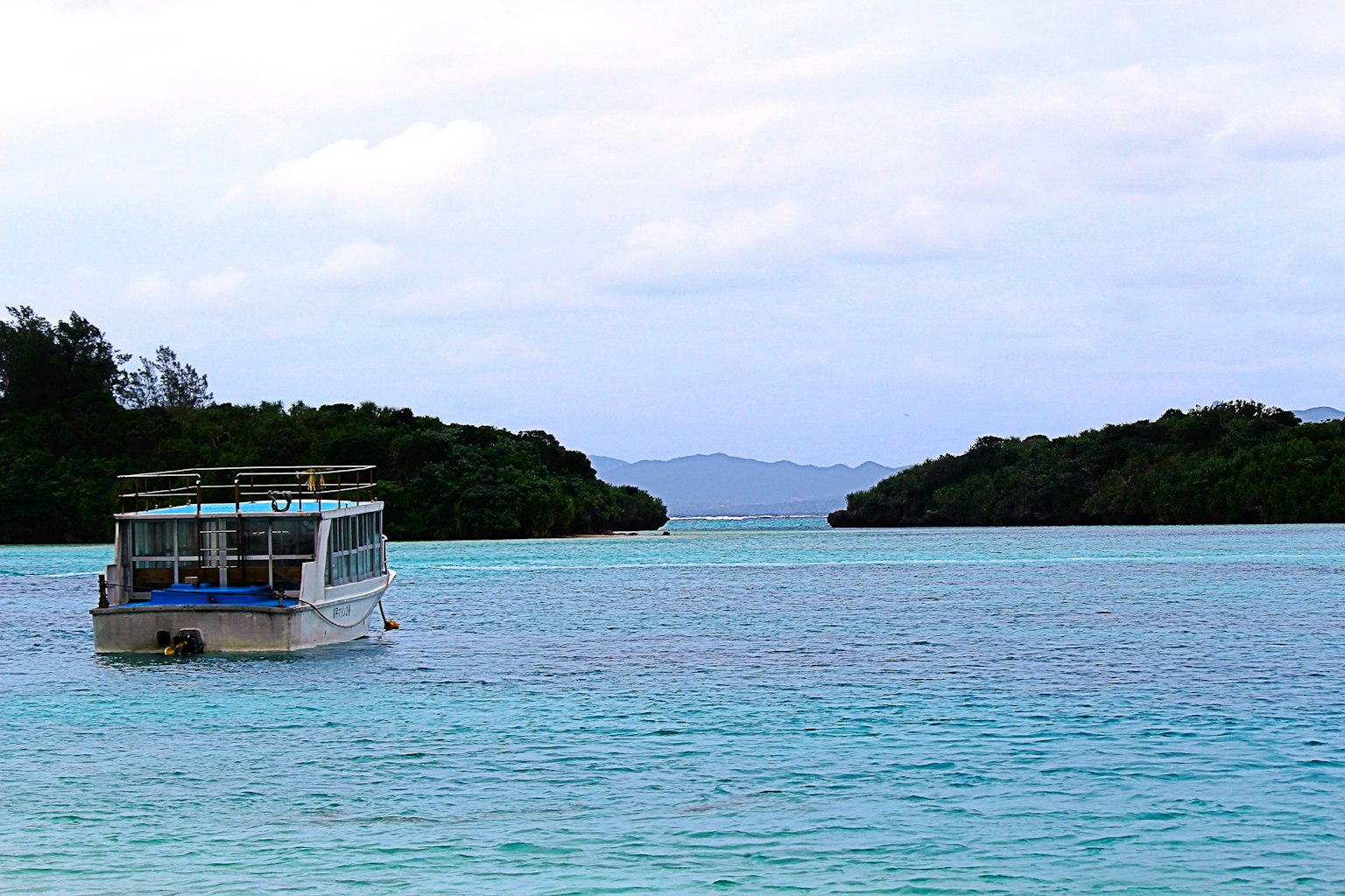 เรือบนทะเลสีเขียวมรกตที่มีเกาะสีเขียวรอบข้าง