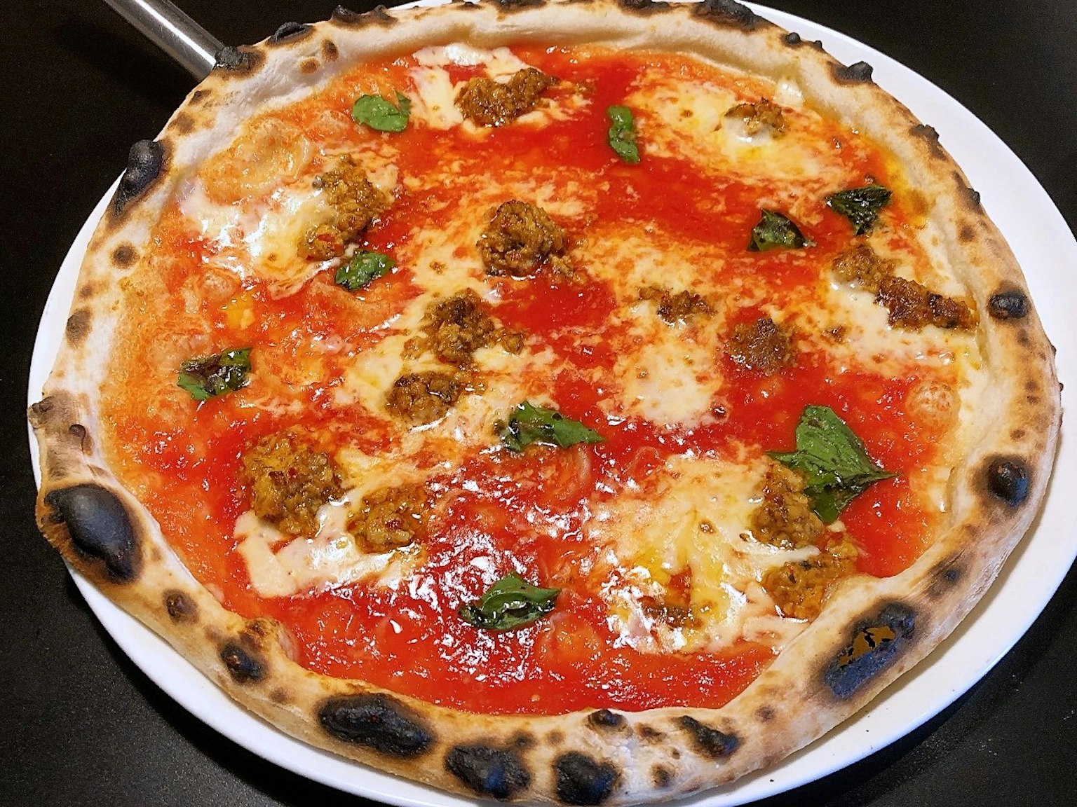 Pizza con salsa di pomodoro e mozzarella con crosta bruciata e foglie di basilico