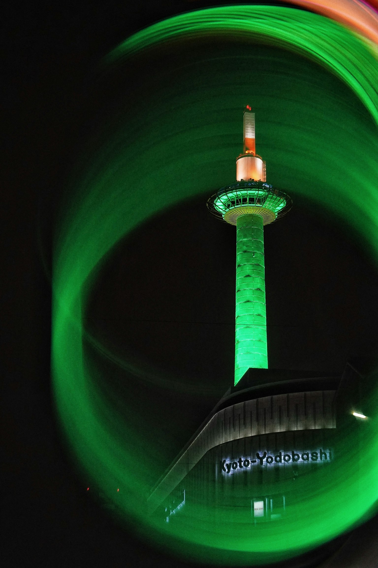 Night view of Tokyo Tower illuminated in green with swirling light effects