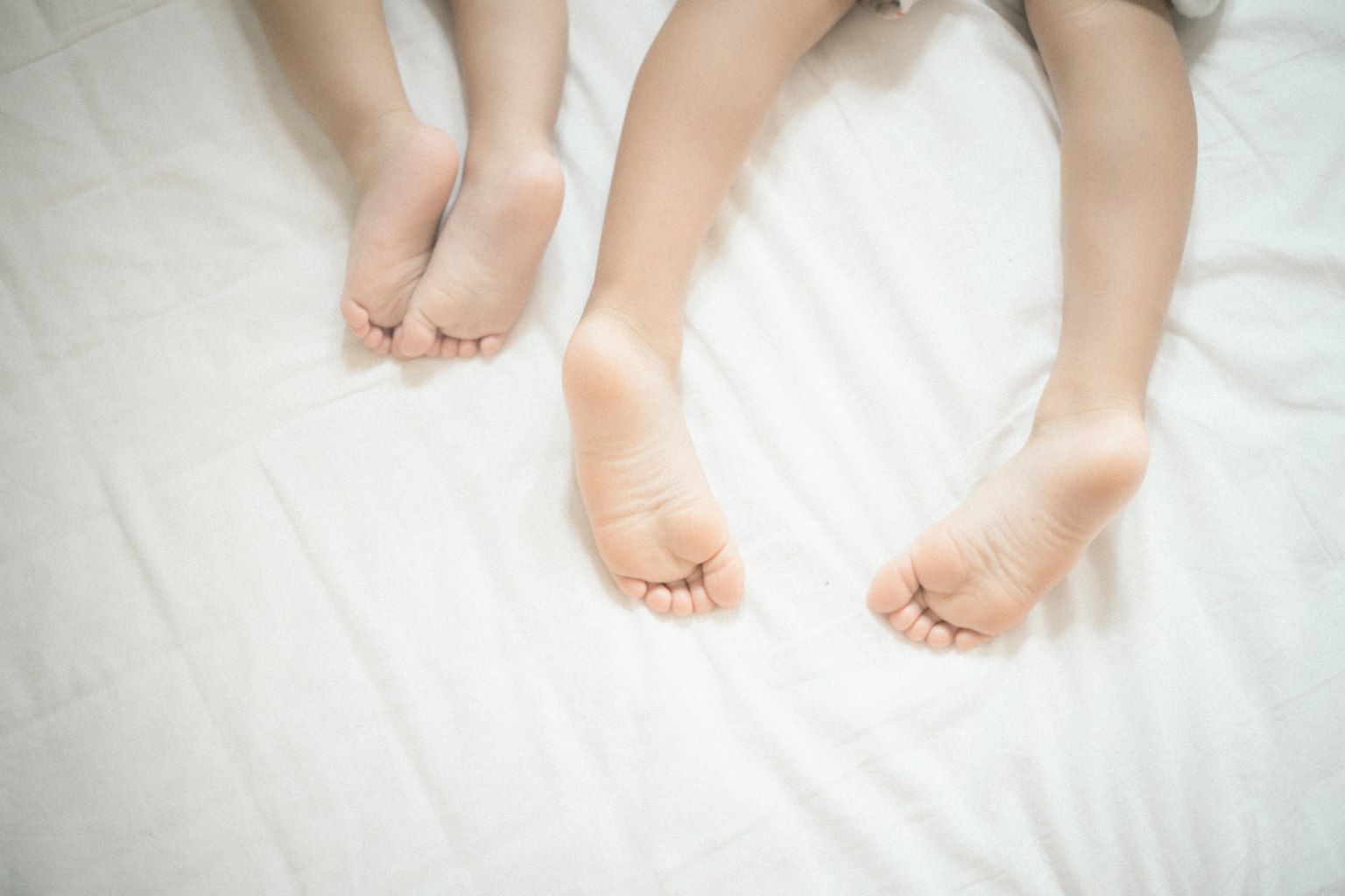 Chân của người lớn và trẻ em resting trên ga trải giường trắng