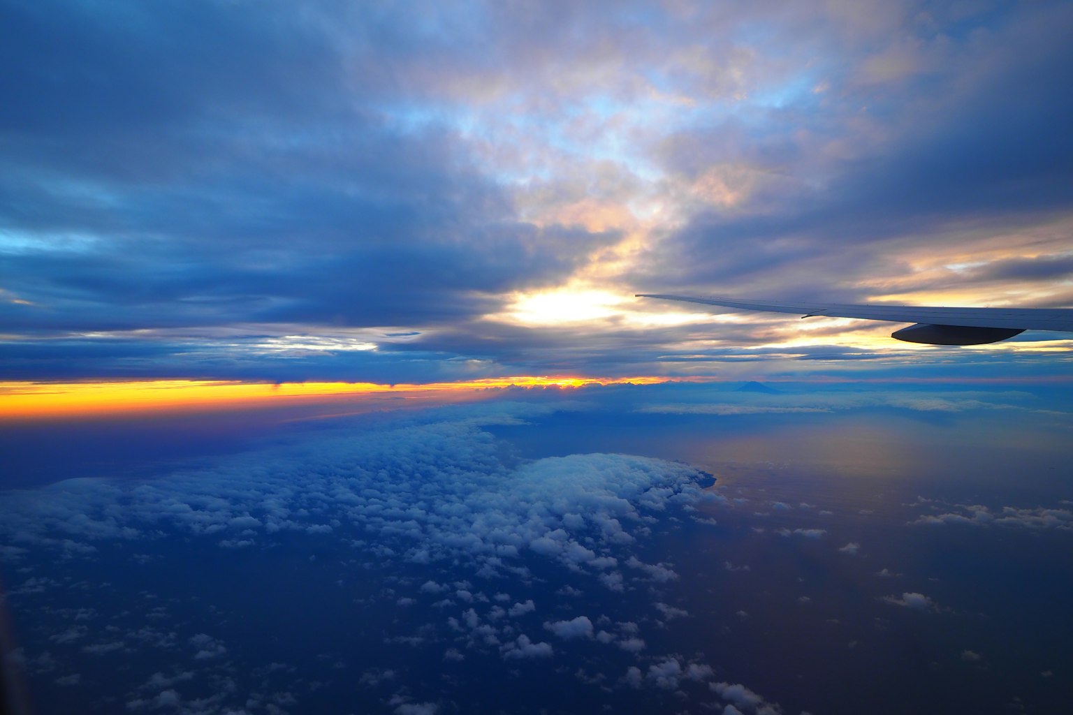 Vue aérienne d'un coucher de soleil vibrant avec des teintes bleues et orange sur des nuages et la mer