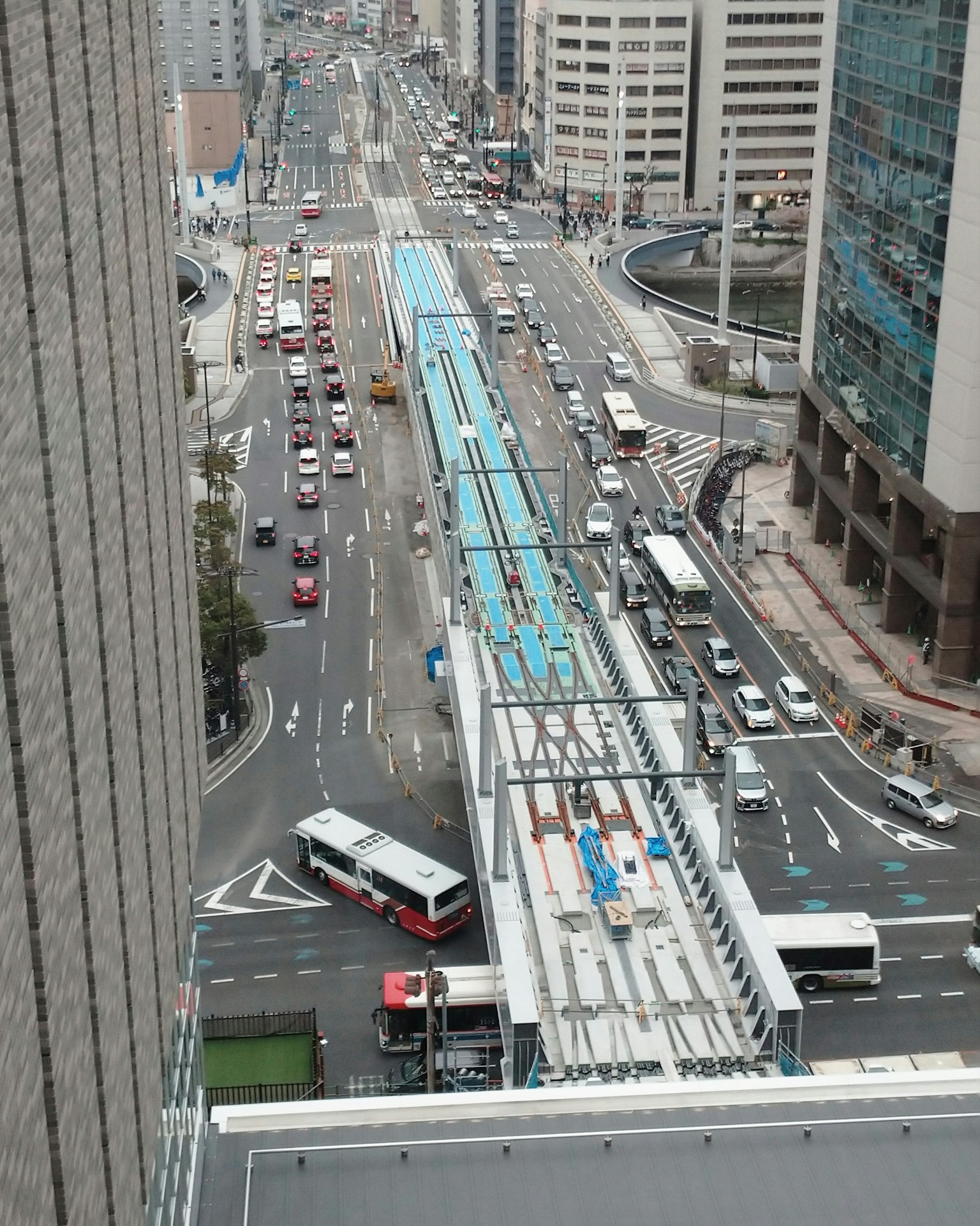 Cảnh nhìn từ trên cao của một con phố đô thị đông đúc giữa các tòa nhà chọc trời với trạm xe buýt và xe cộ