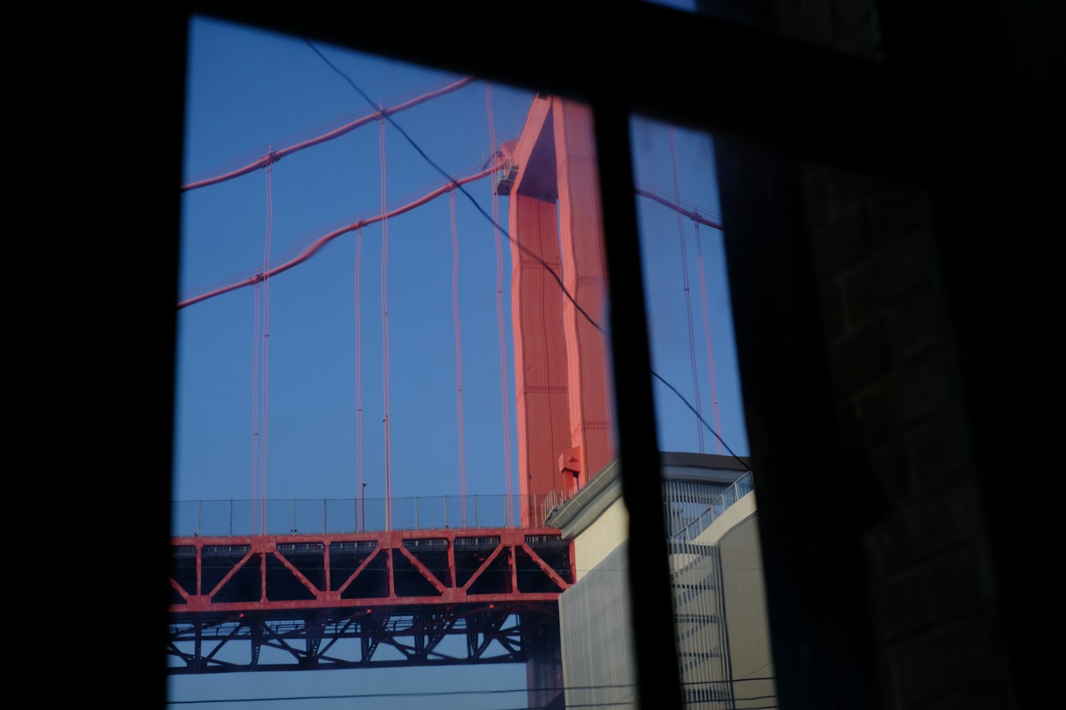 Vue d'un pont rouge à travers une fenêtre avec un ciel bleu clair