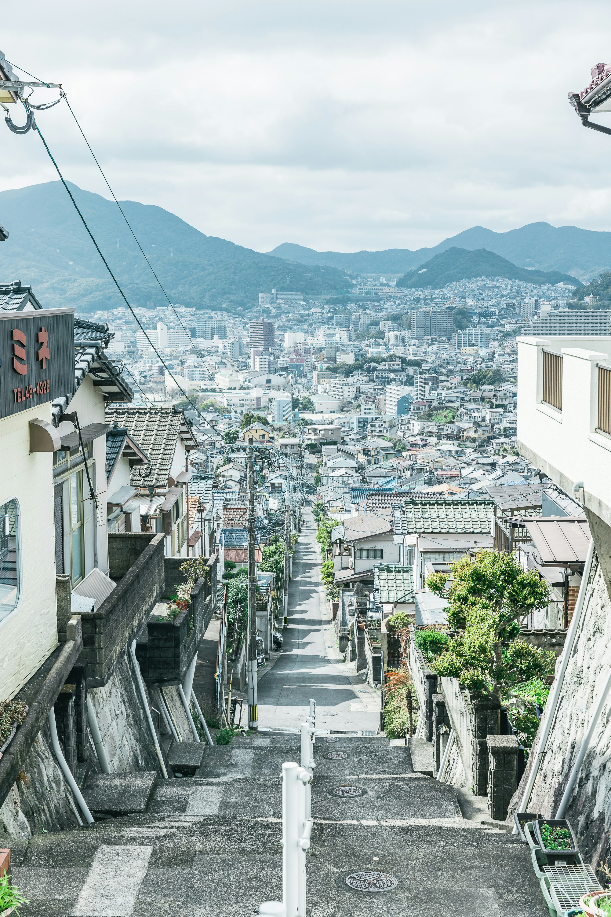 坂道の路地と街並み、遠くに山並みが見える眺望