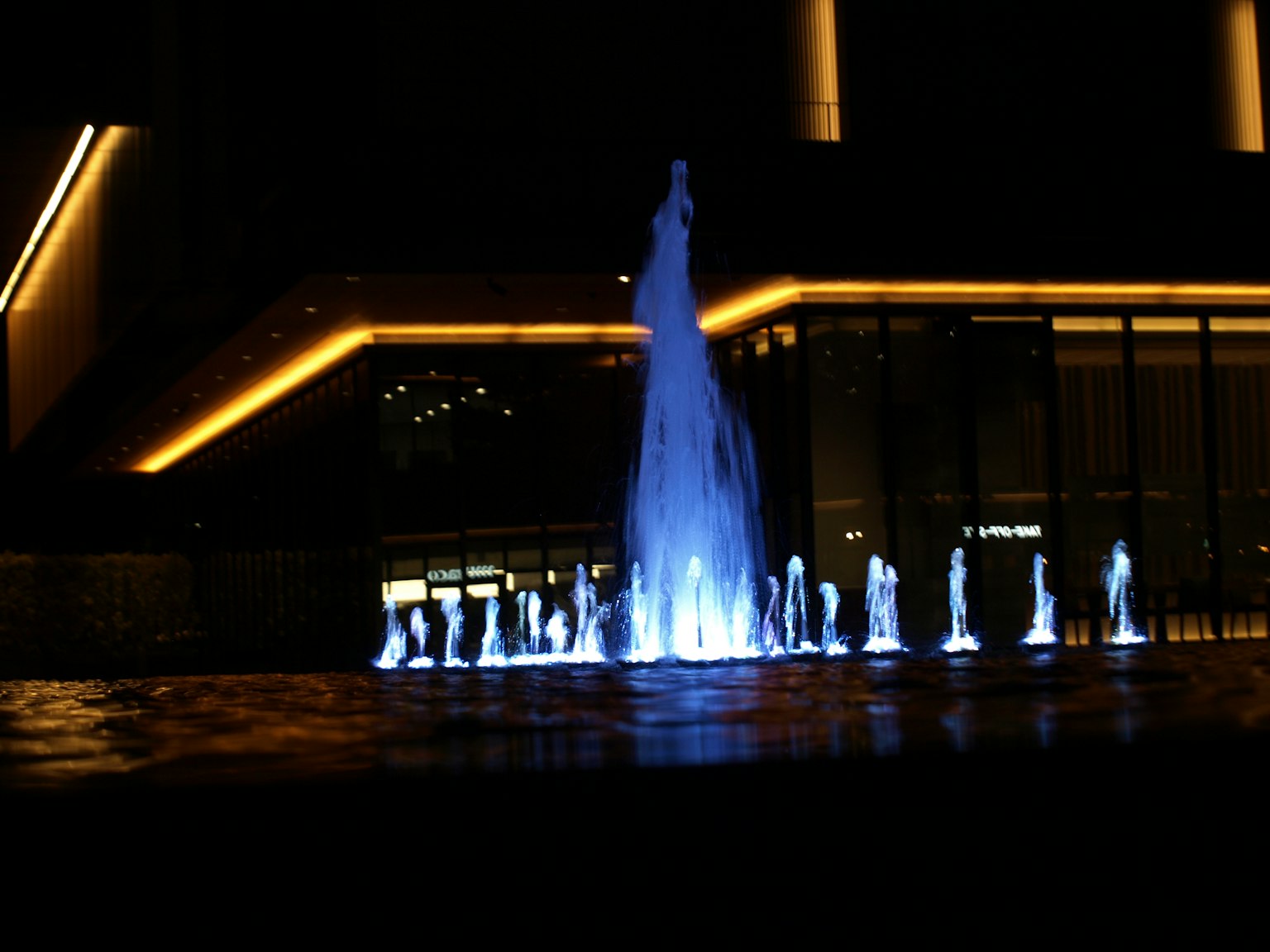Beleuchteter Brunnen bei Nacht mit blauen Lichtern