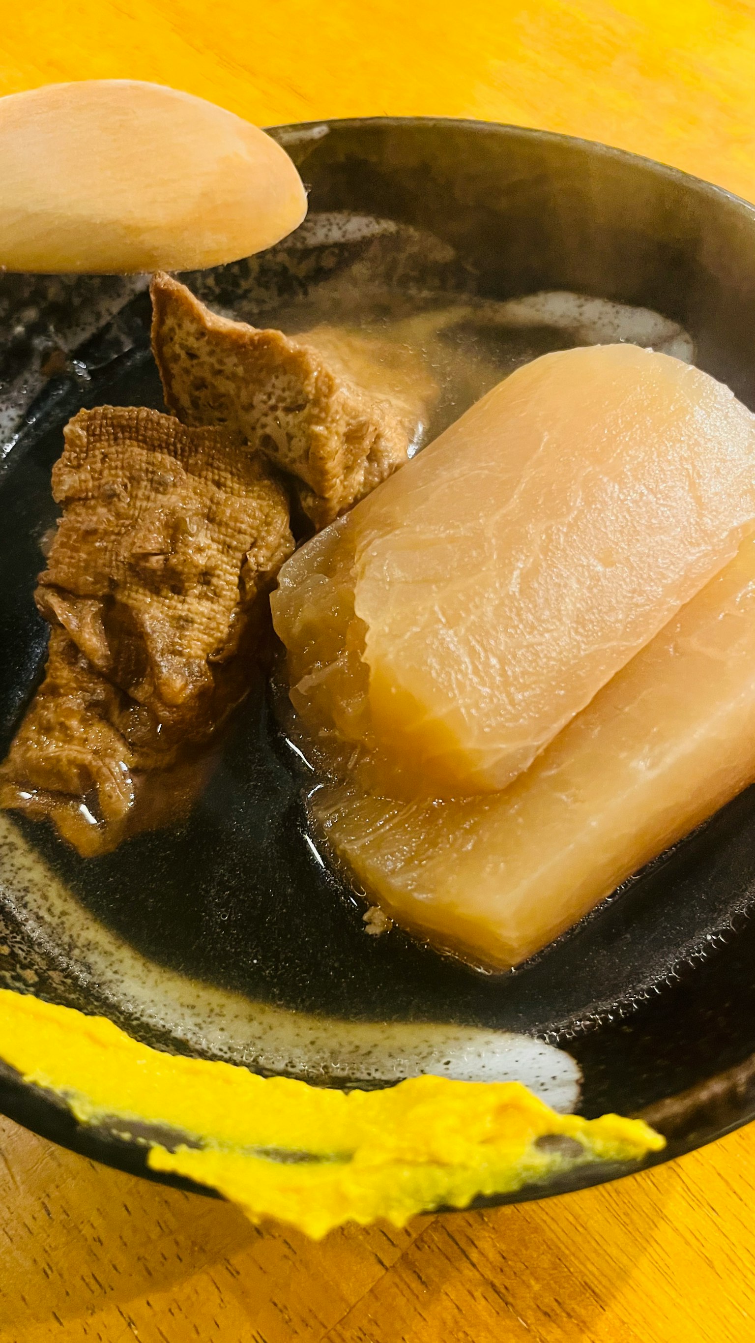 Braised daikon and meat in a black bowl
