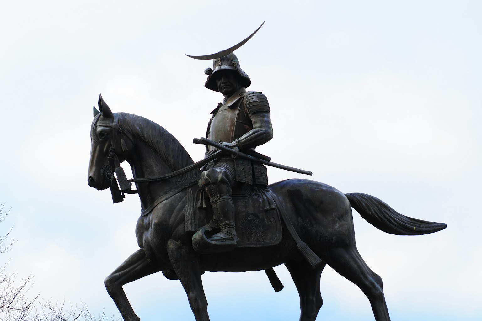 Estatua de bronce de un samurái a caballo bajo un cielo azul