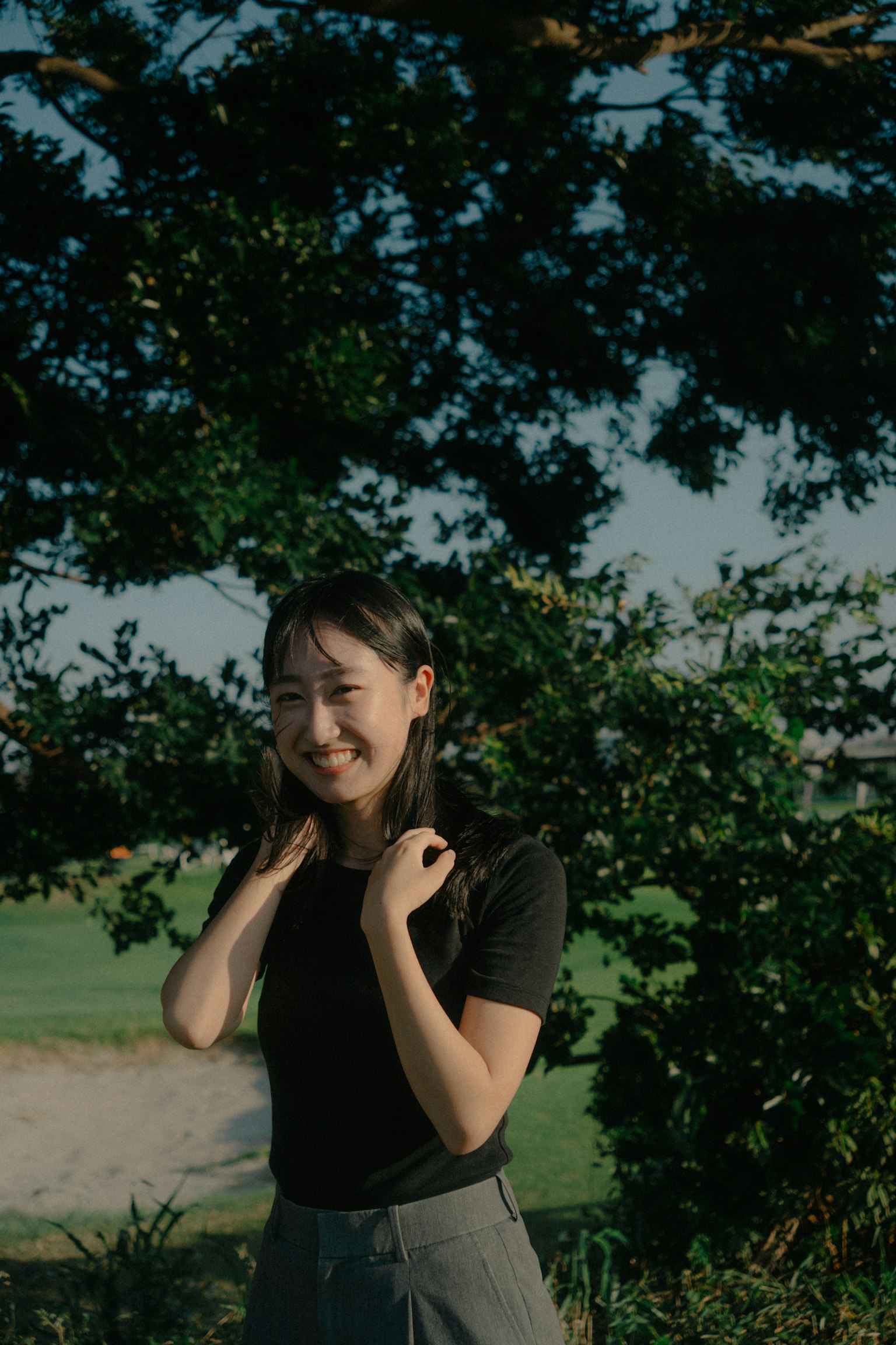 หญิงสาวยิ้มในเสื้อสีดำท่ามกลางธรรมชาติ