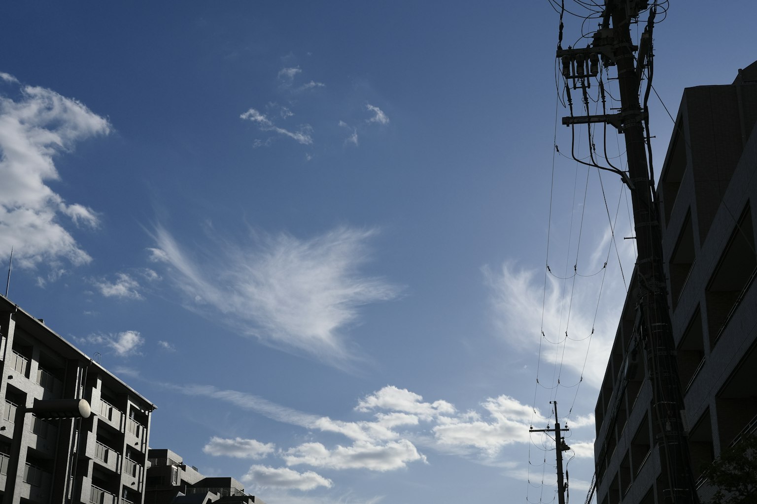 A silhouette of buildings under a blue sky with white clouds