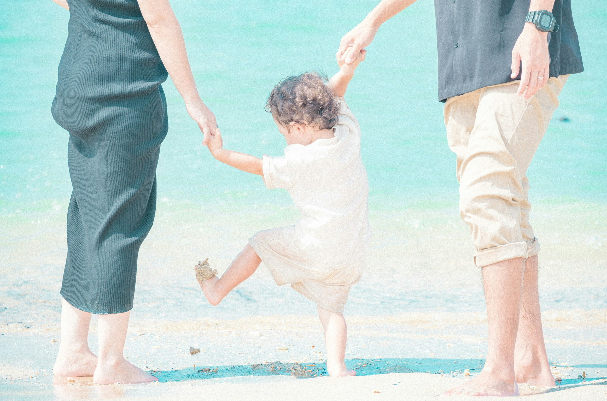 Familie hält sich am Strand an den Händen