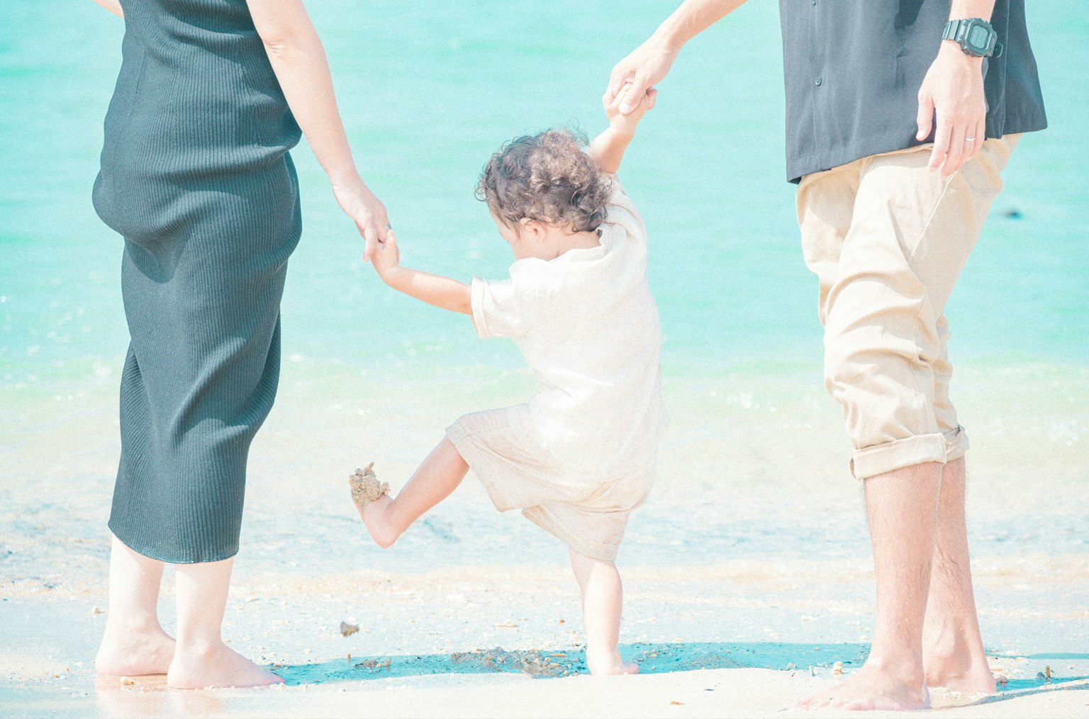 Family enjoying time at the beach child playfully stepping into the water