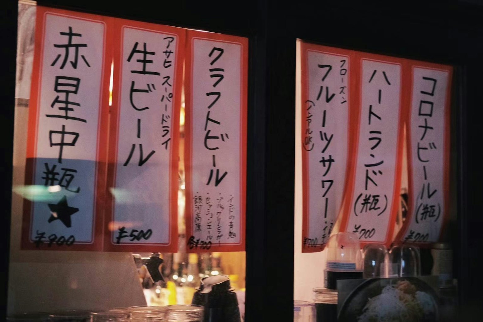 Escena nocturna de un tablero de menú de izakaya japonés que muestra varias bebidas