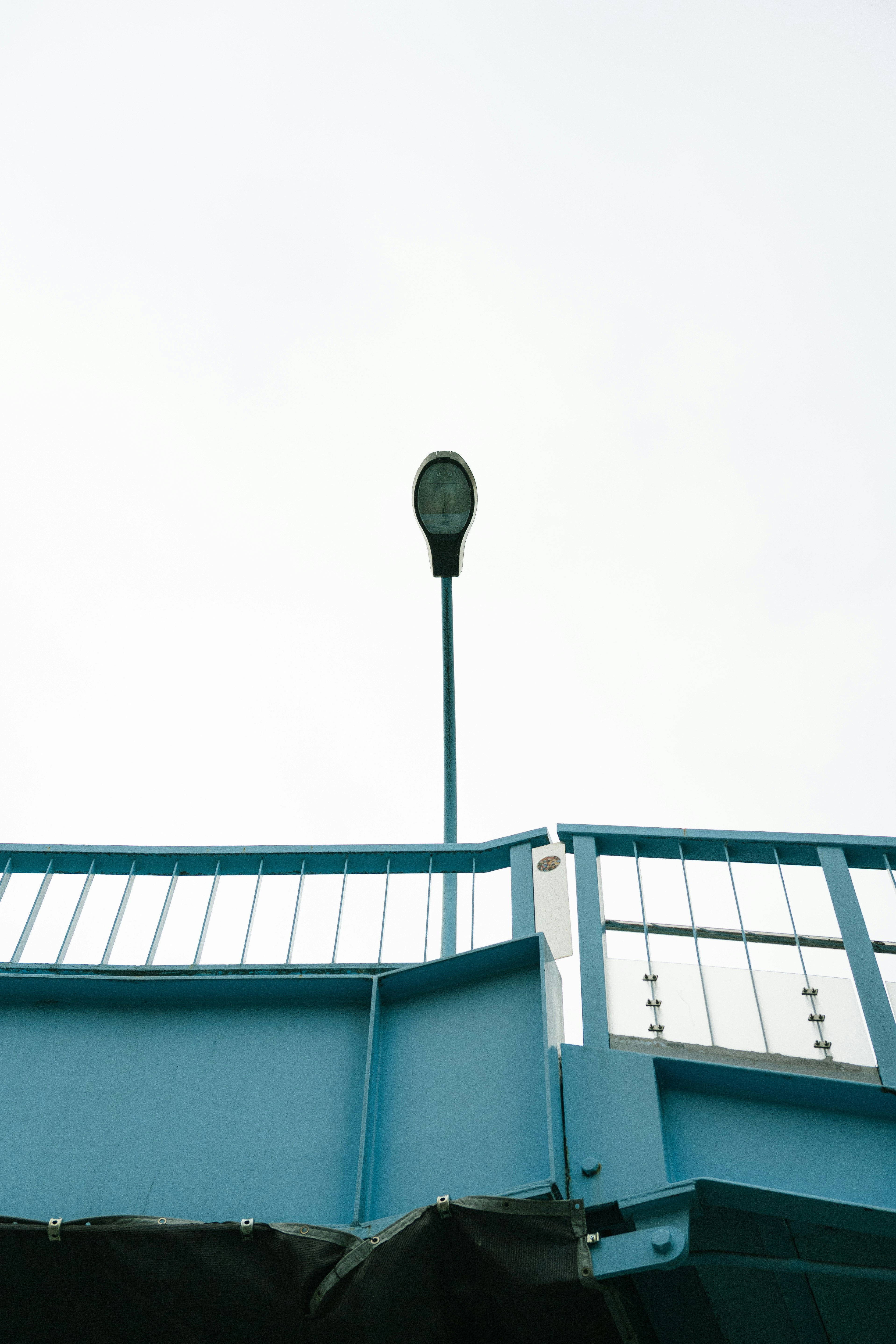 composition avec un lampadaire sur des garde-corps bleus sous un ciel clair