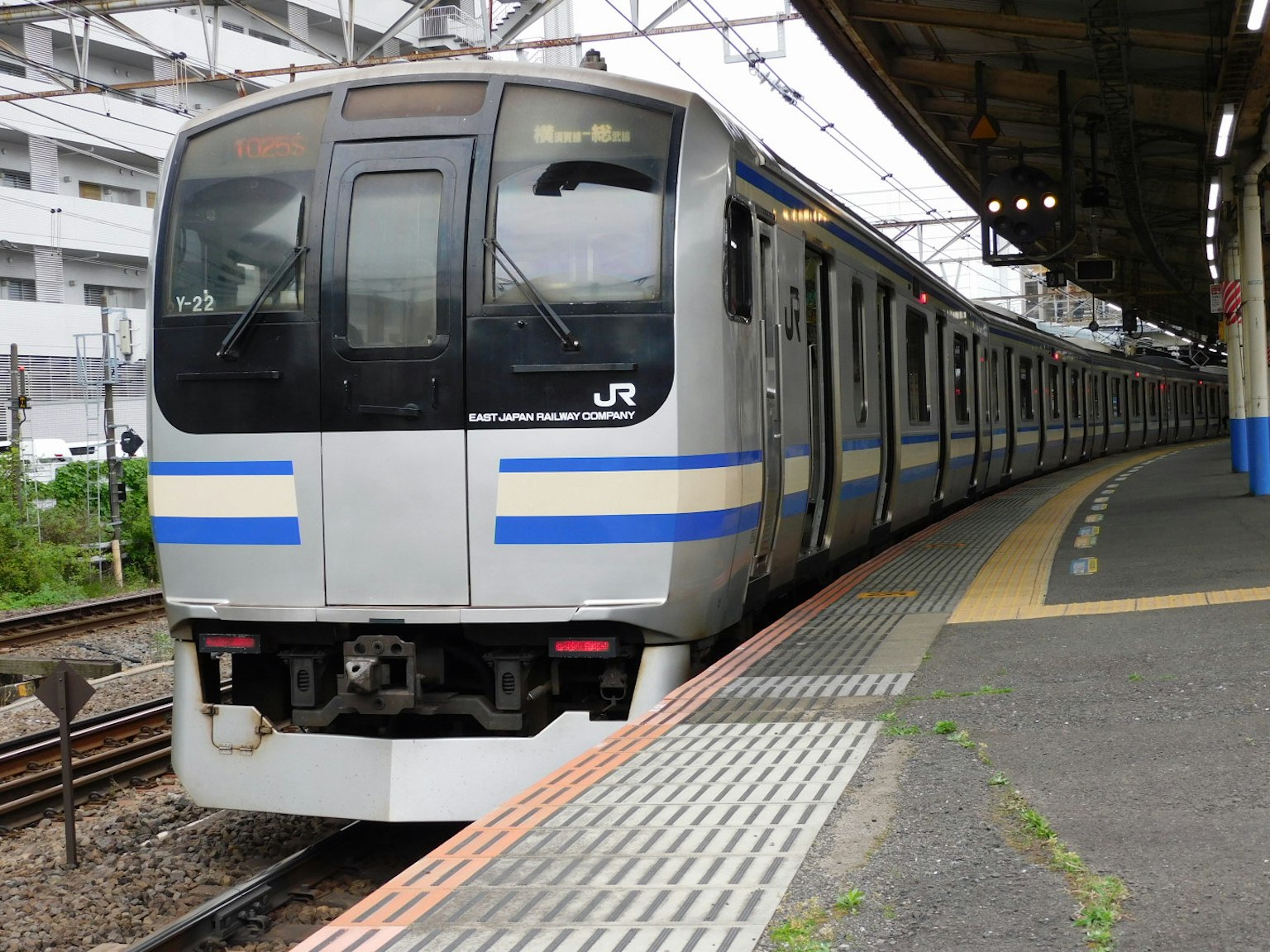 日本列車在車站停靠，帶有藍色條紋