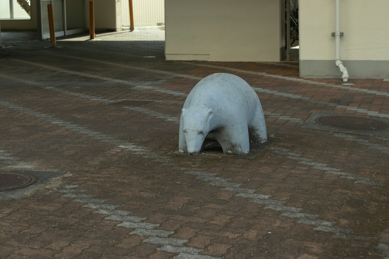Una scultura di orso bianco è seduta su un pavimento pavimentato