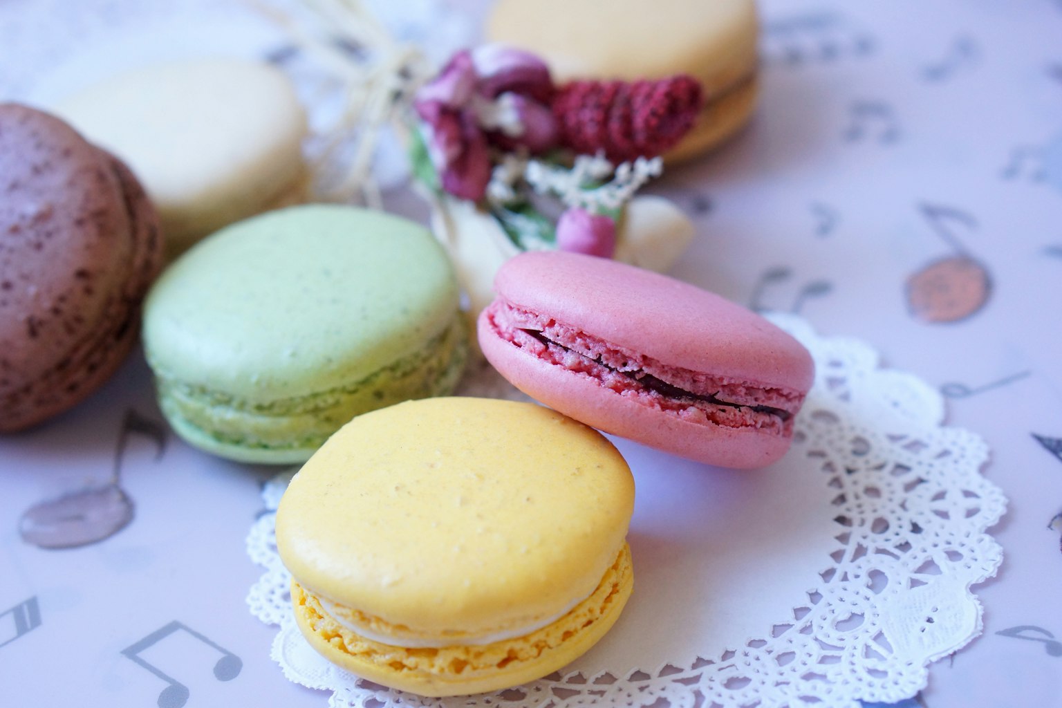 Bunte Macarons auf einem Spitzenuntersetzer mit floralen Akzenten angeordnet