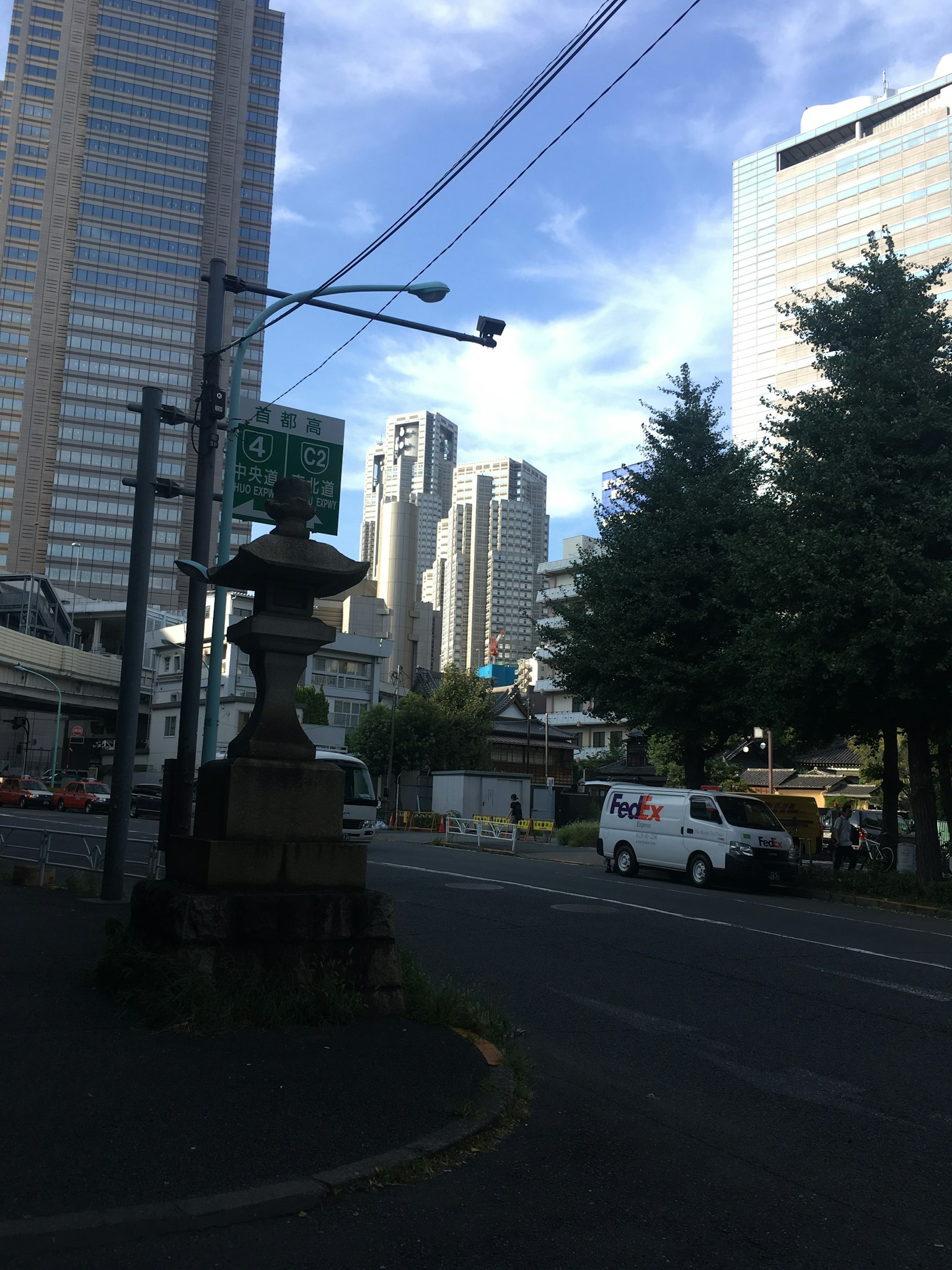 Una antigua linterna de piedra en una intersección urbana con rascacielos al fondo