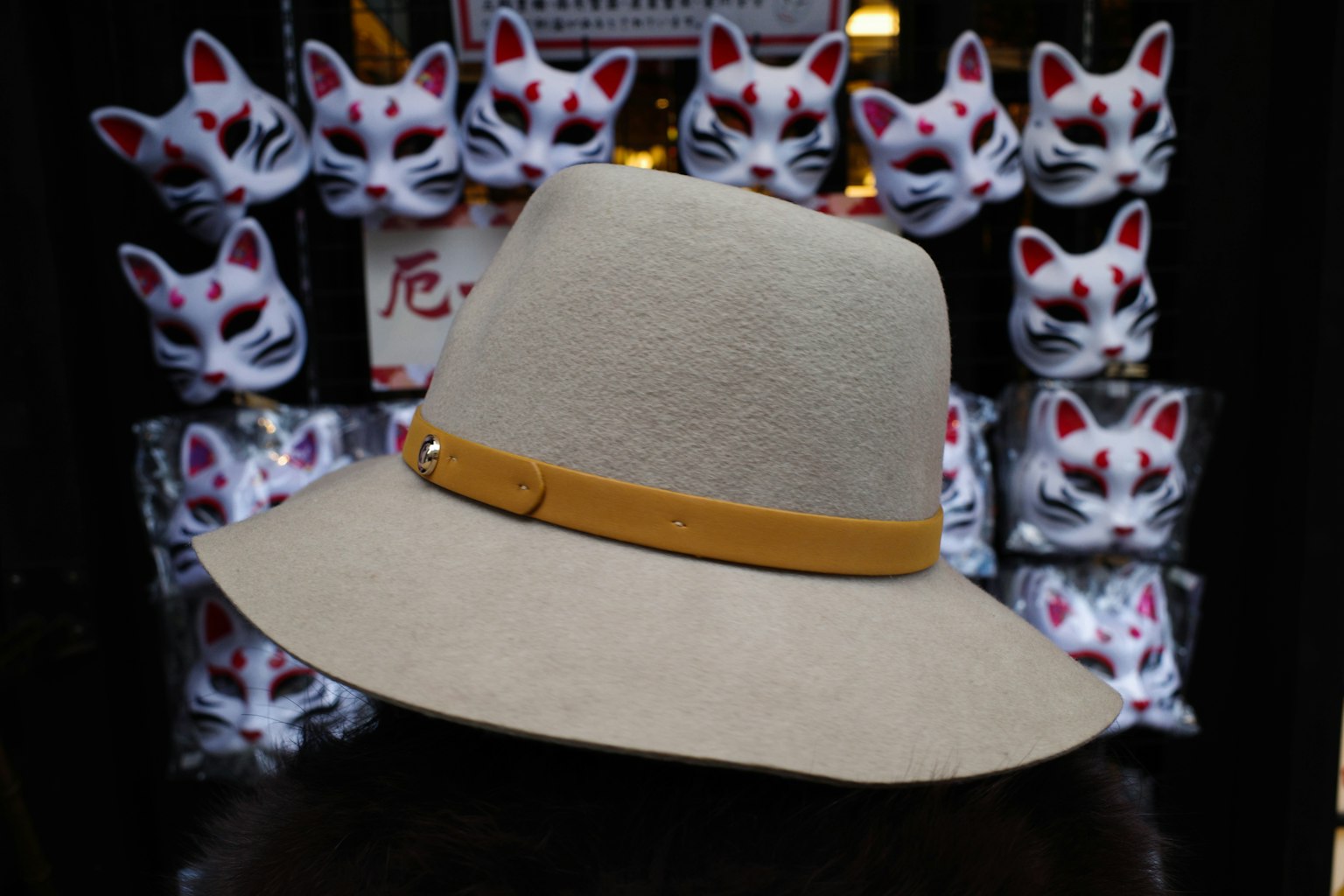 Sombrero de fieltro con banda amarilla frente a máscaras de zorro
