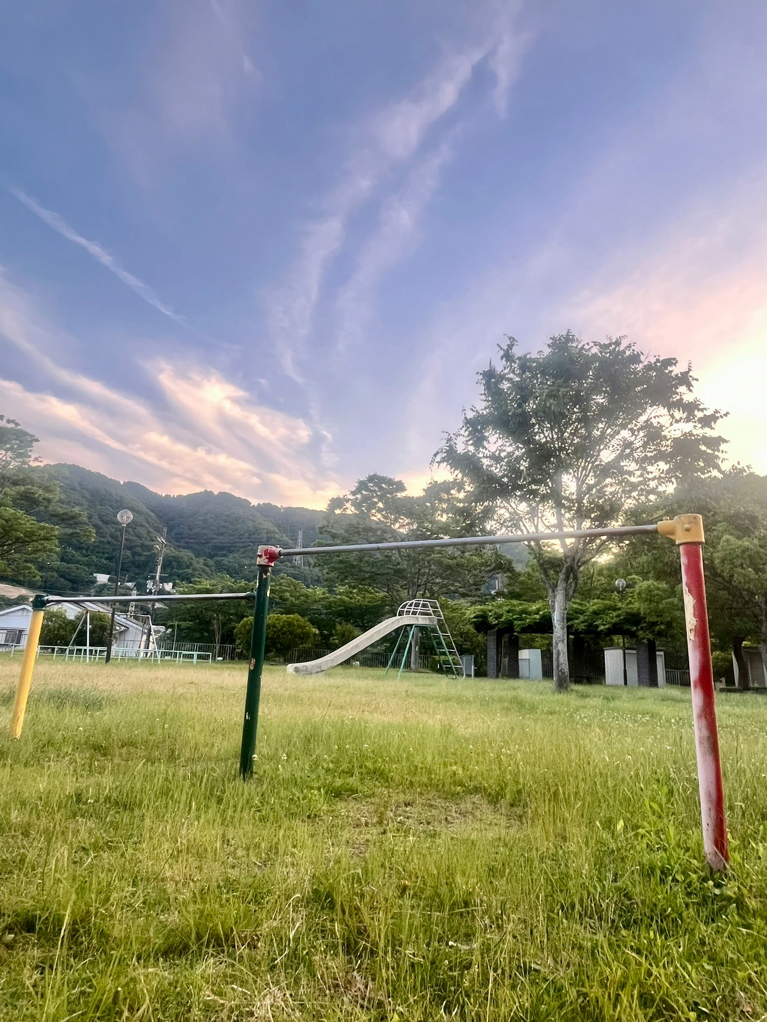 夕暮れの公園で遊具と芝生が広がる風景