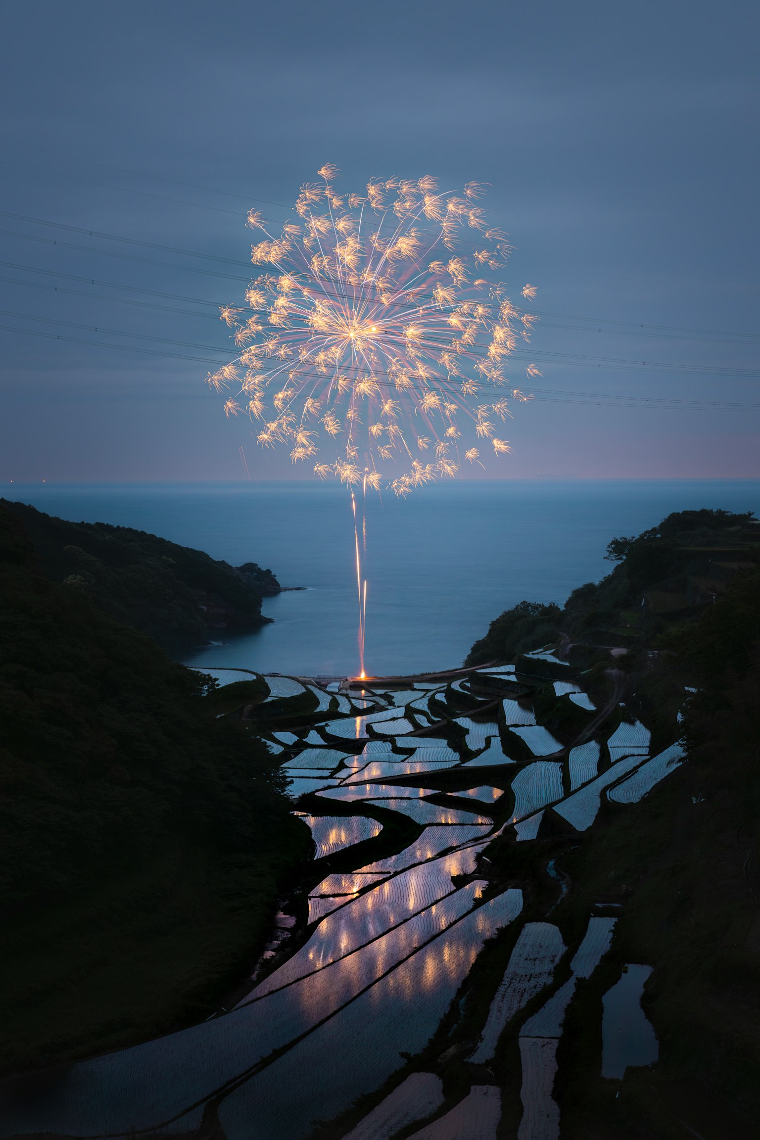 Un paesaggio sereno con terrazze di riso che riflettono un bagliore simile a fuochi d'artificio contro il cielo serale