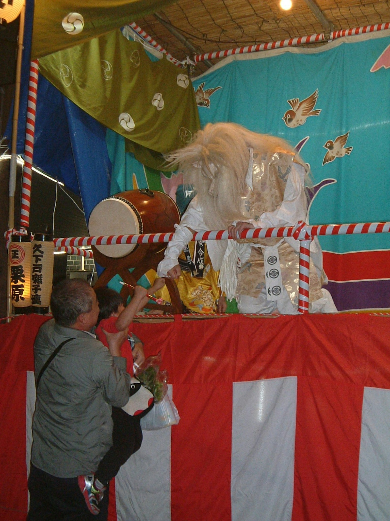 祭りの屋台で人が神輿に花を捧げている様子