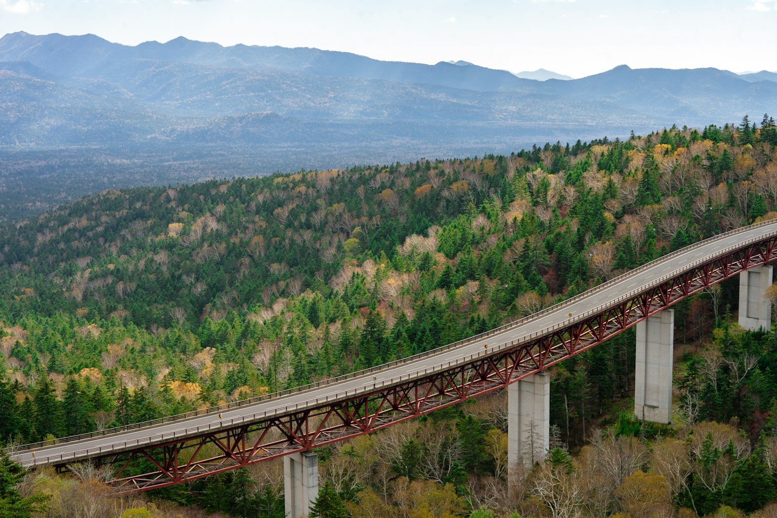 Panoramablick auf eine lange Brücke über grüne Berge
