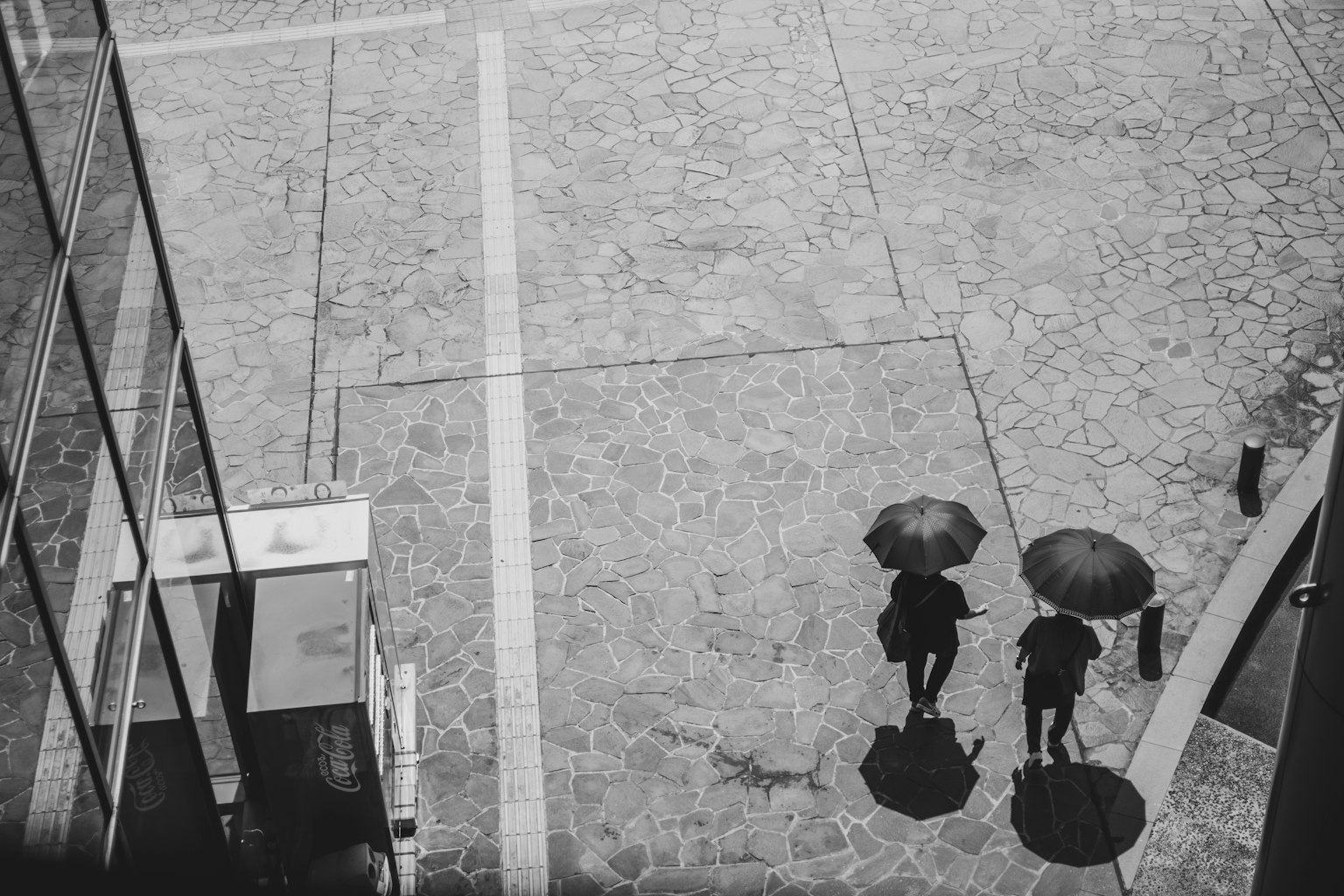 Foto in bianco e nero di due persone che camminano con ombrelli