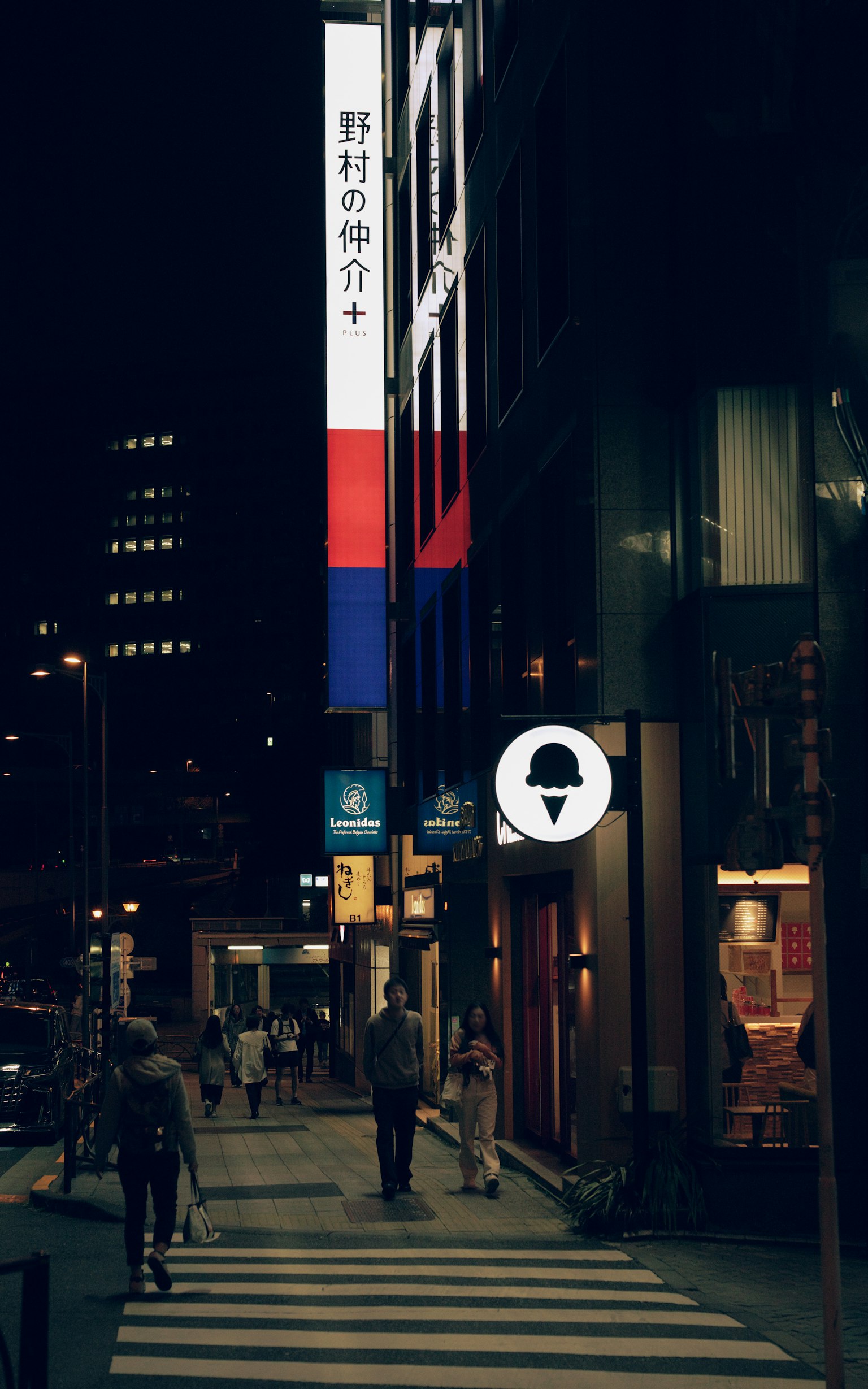 Personas caminando en una calle de la ciudad por la noche con carteles coloridos
