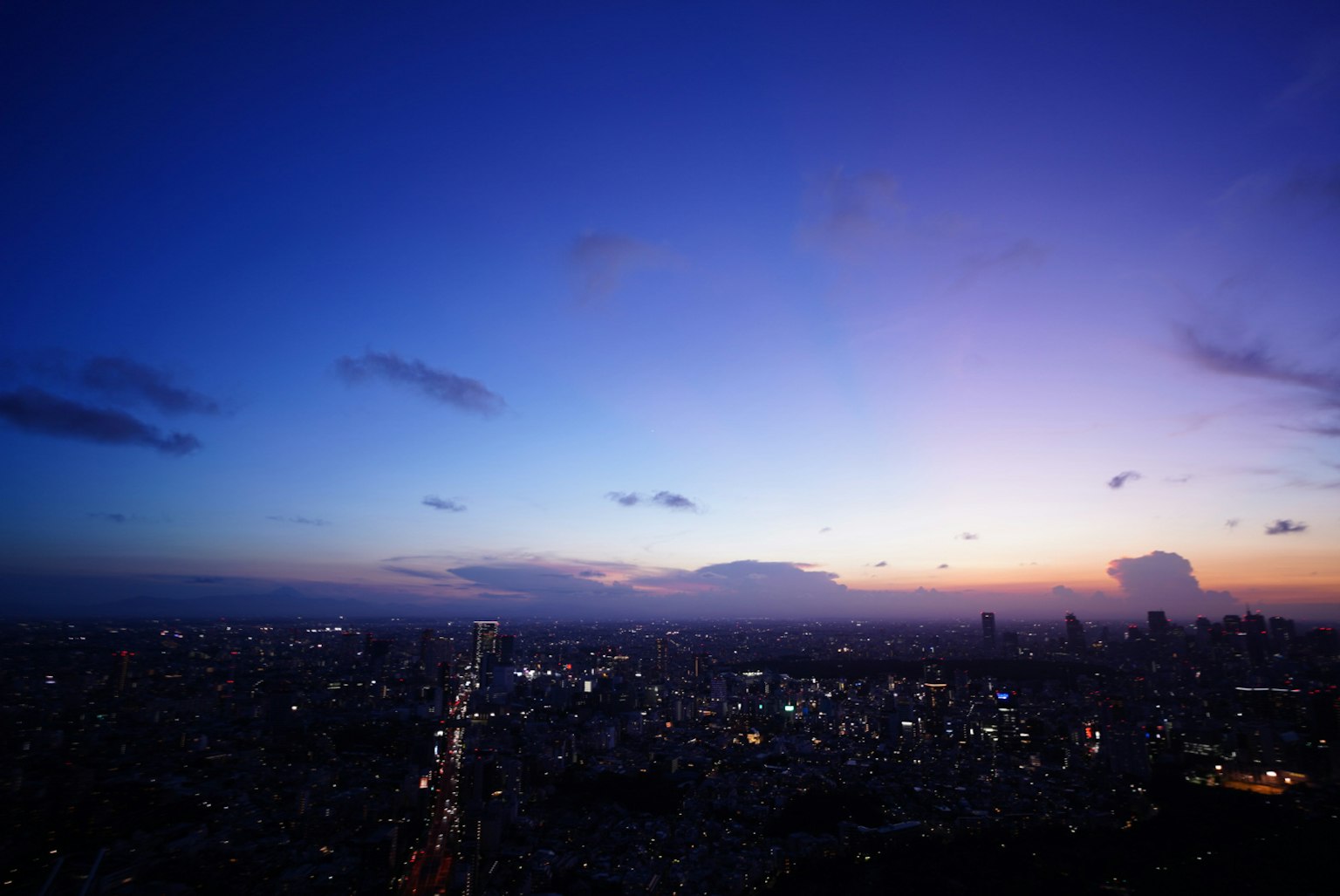 ทิวทัศน์พาโนรามาของเมืองในยามพลบค่ำท้องฟ้าสีน้ำเงินและม่วงพร้อมแสงไฟเมืองที่เปล่งประกาย