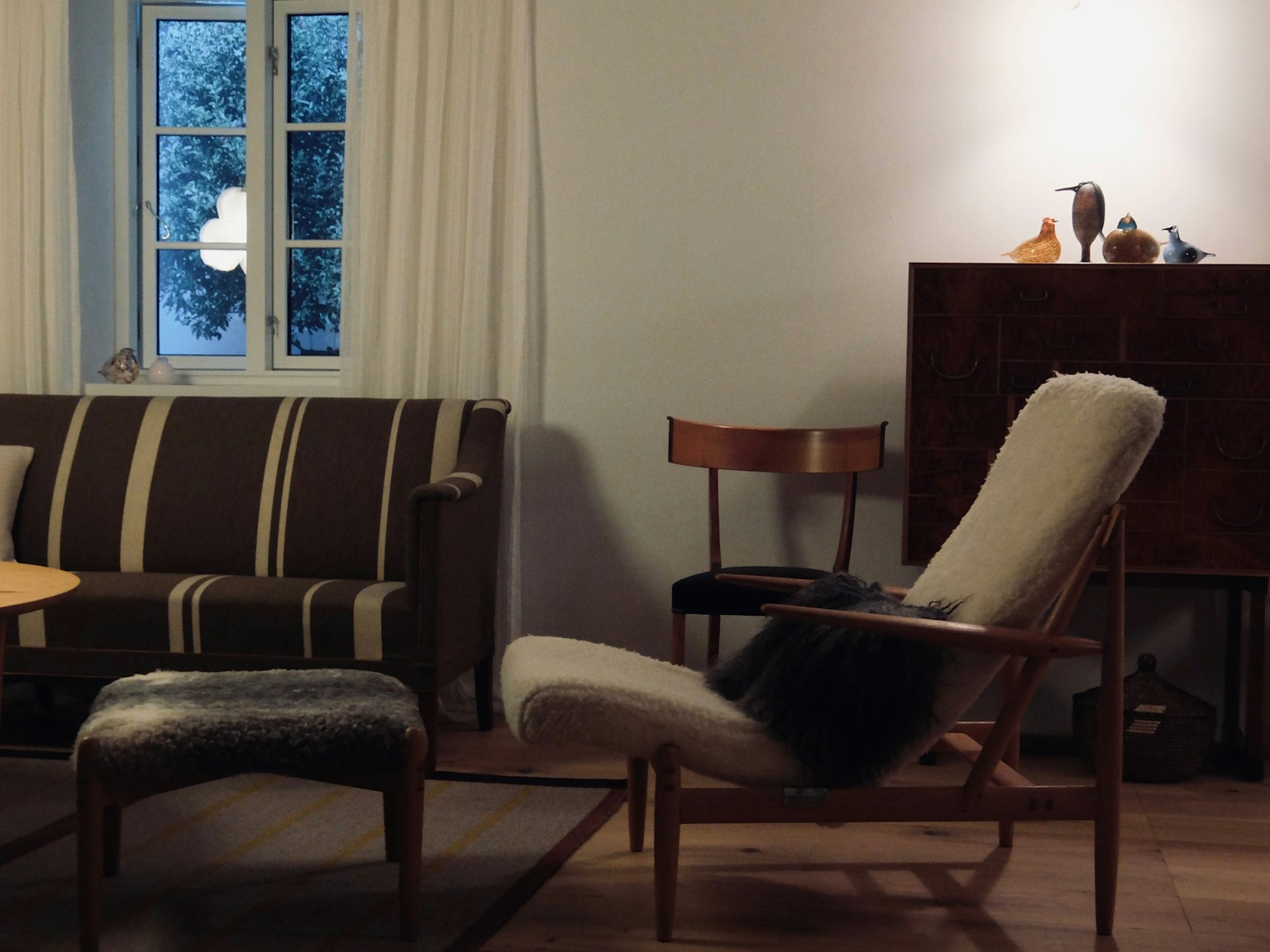 Esquina acogedora de una sala de estar con sofá a rayas y silla de madera
