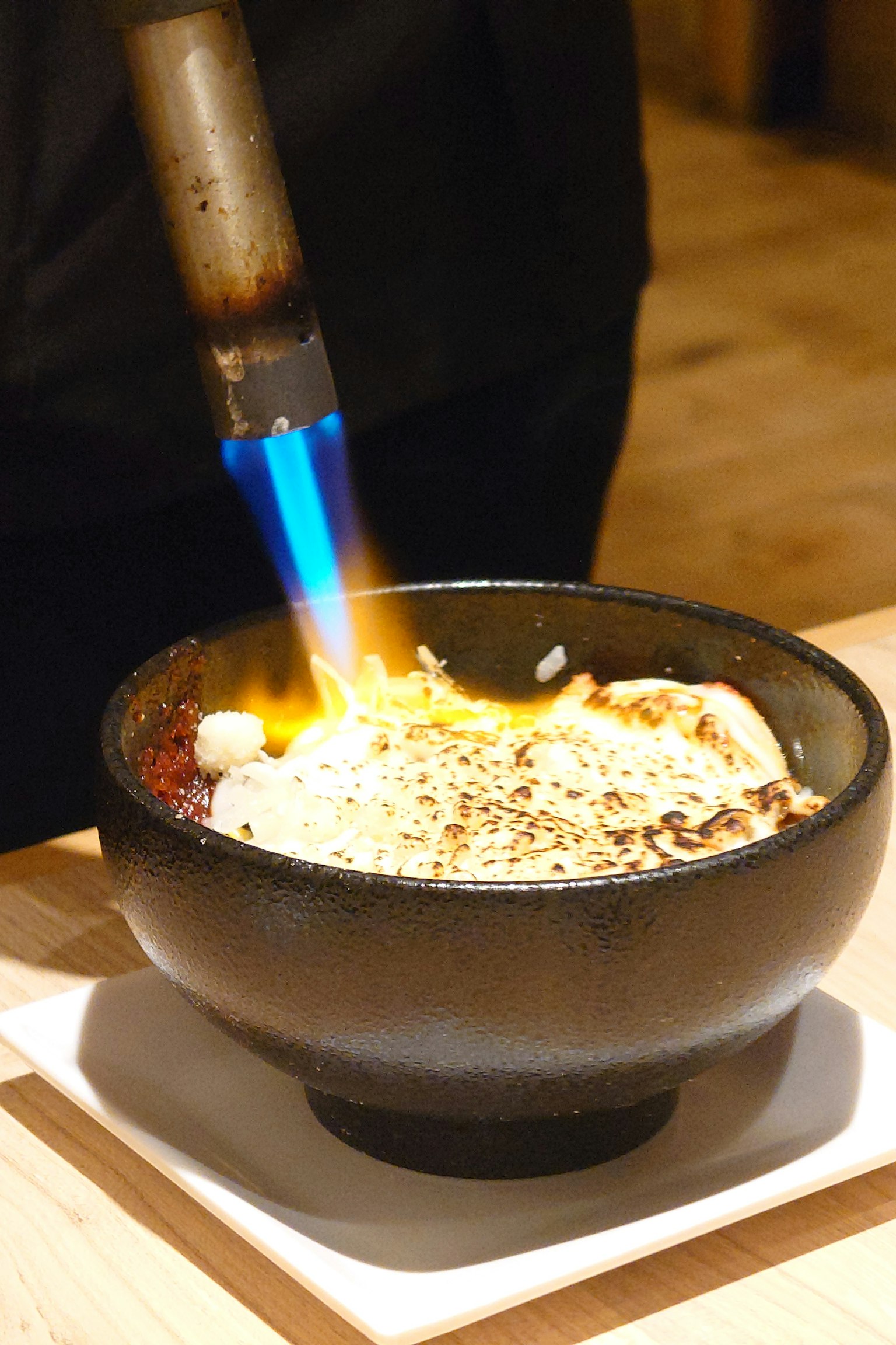 Una ciotola nera con cibo che viene bruciato con una fiamma blu