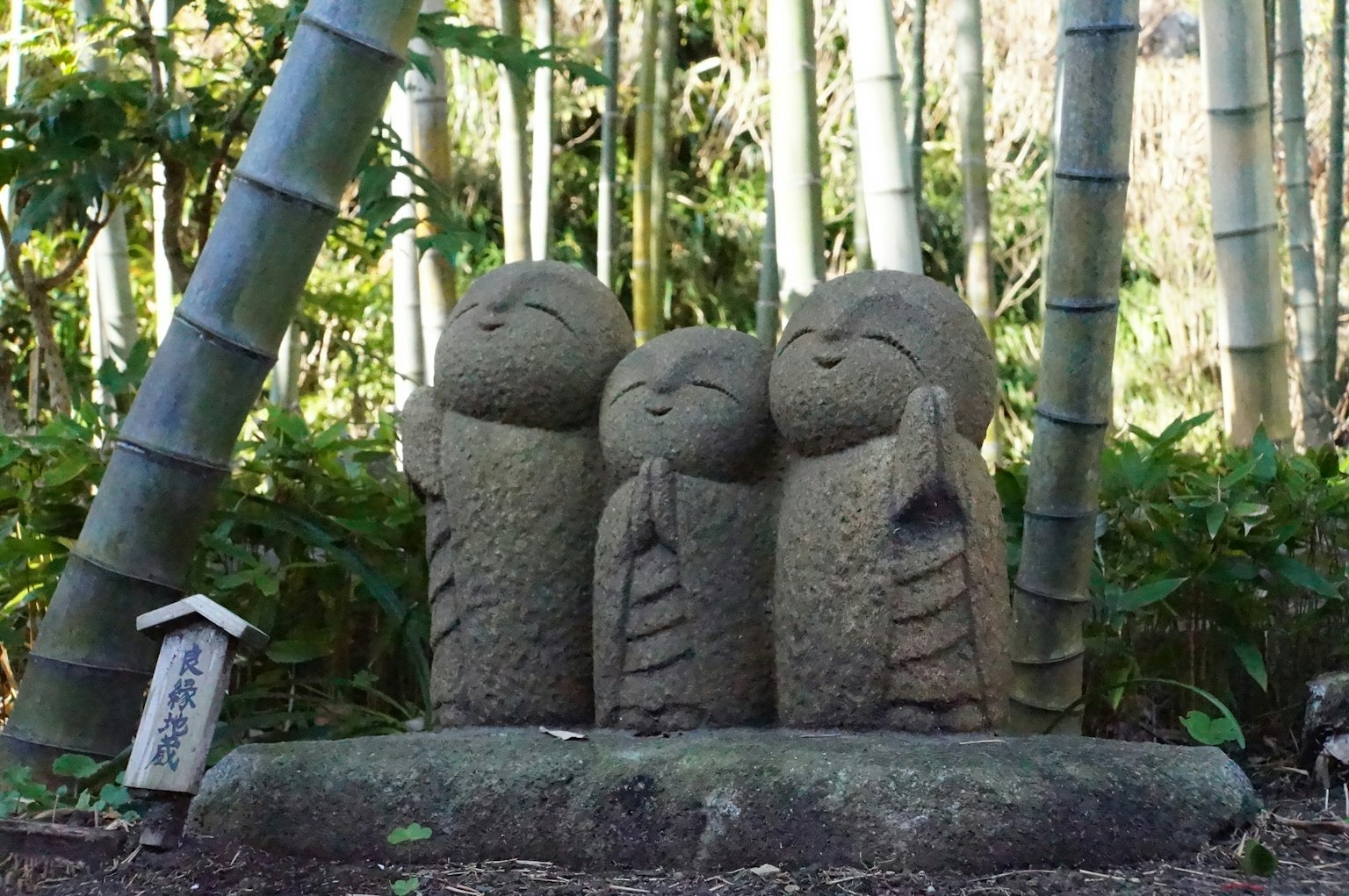 รูปปั้นหินสามตัวที่มือประนมในป่าไผ่