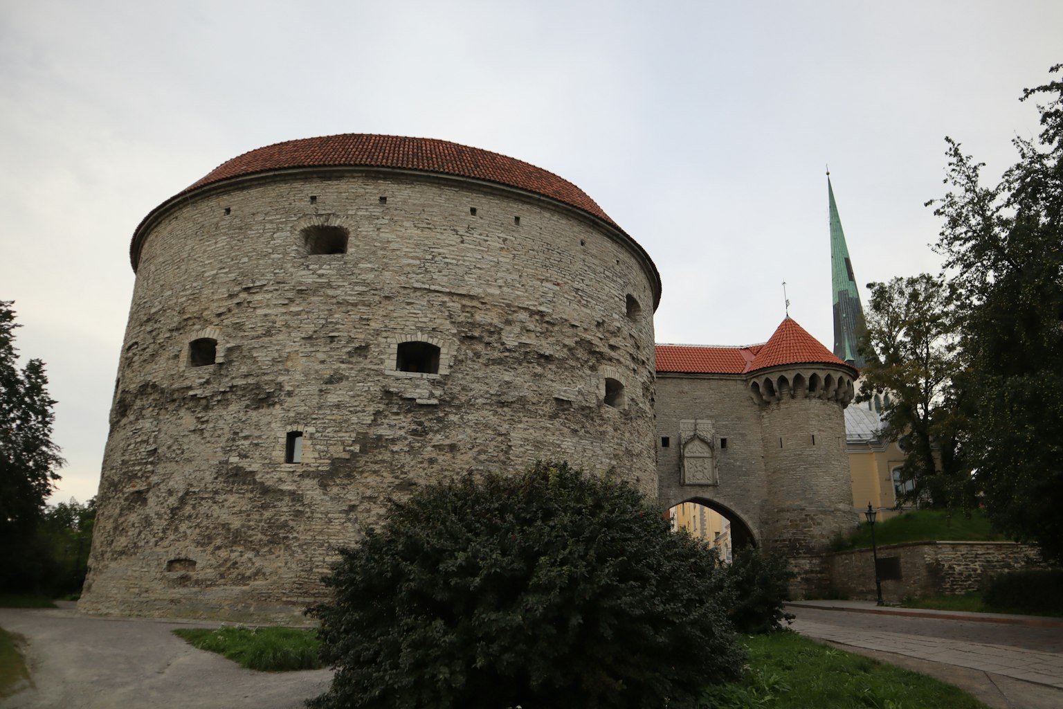 Landschaft mit einem runden Steinturm und rotem Dach